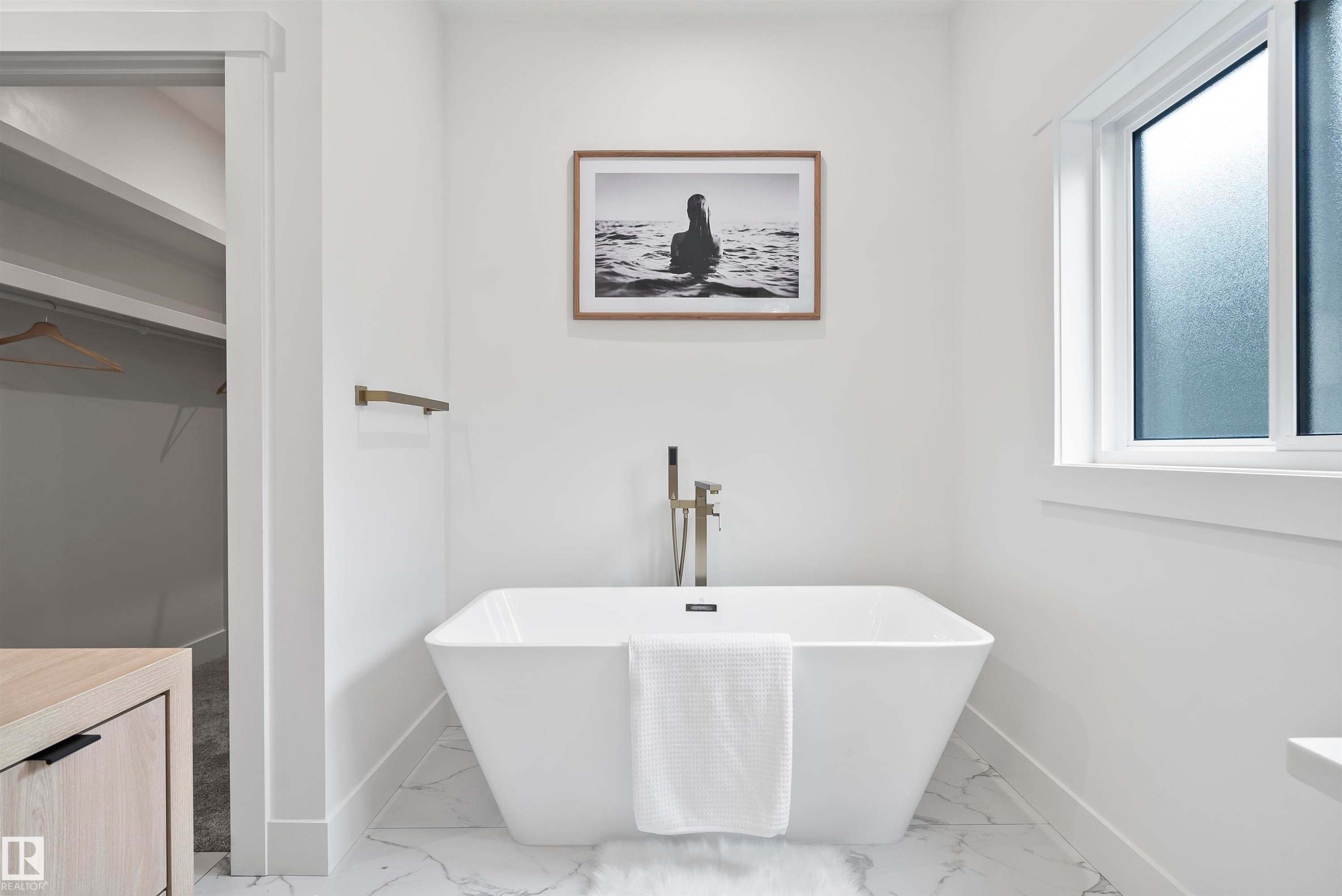 Freestanding soaking tub with floor-mounted faucet, marble-finish tile flooring, recessed lighting, and a window with frosted glass - 13152 187 Avenue, Edmonton, AB