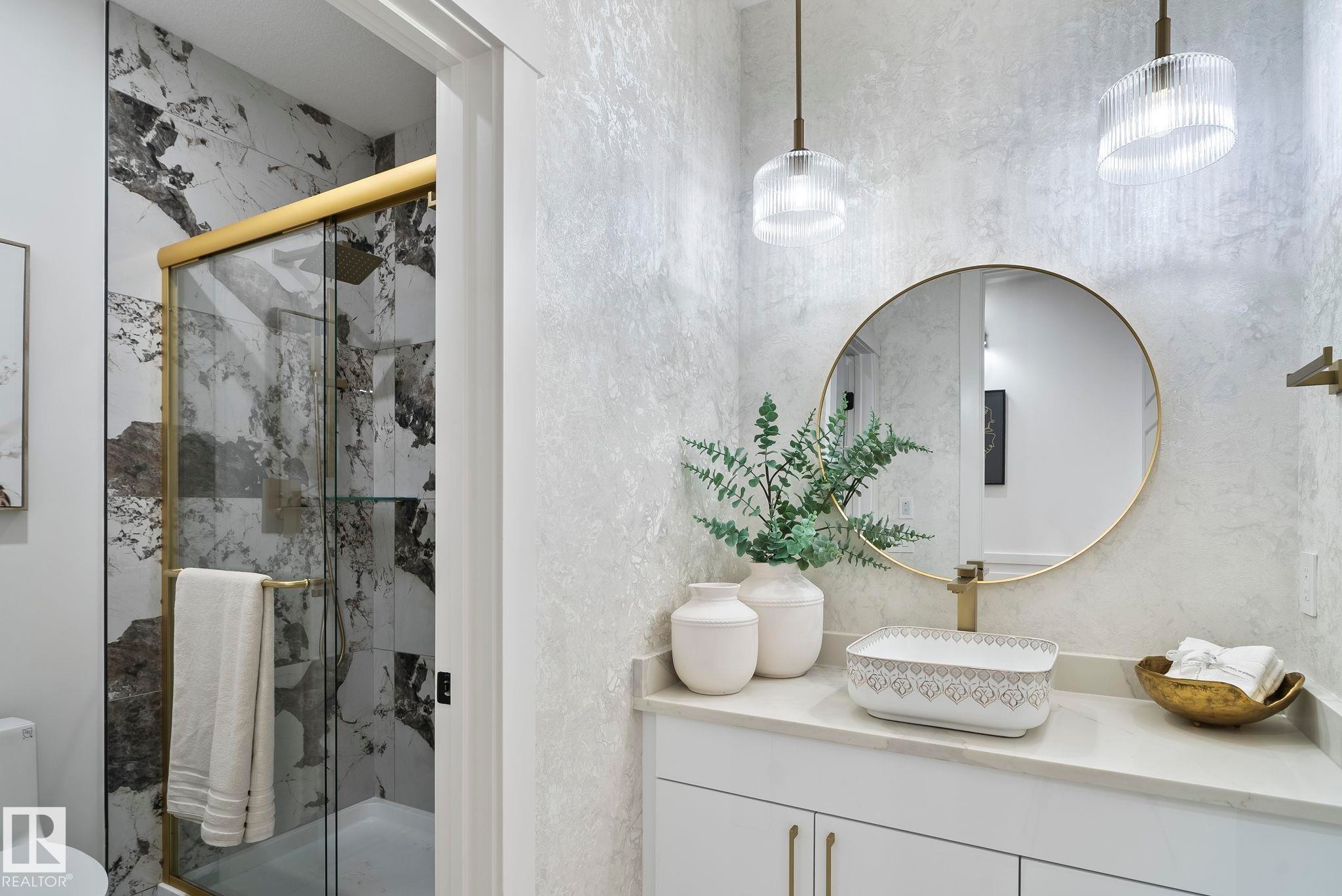 Bathroom featuring a gold-framed shower enclosure, large format marble-look tile, vessel sink, gold-toned fixtures, and pendant lighting - 13152 187 Avenue, Edmonton, AB