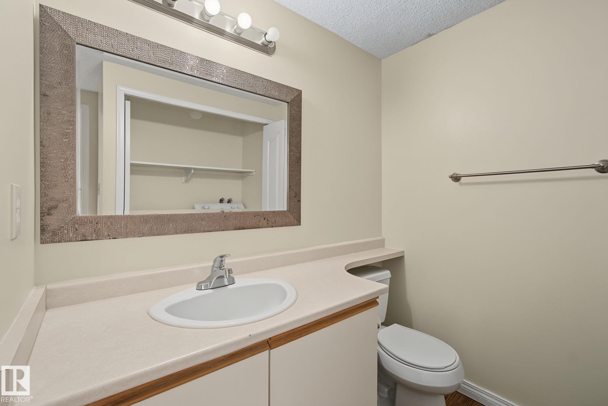 Bathroom vanity featuring a light-colored countertop, integrated sink, and chrome faucet - 4259 29 Avenue, Edmonton, AB