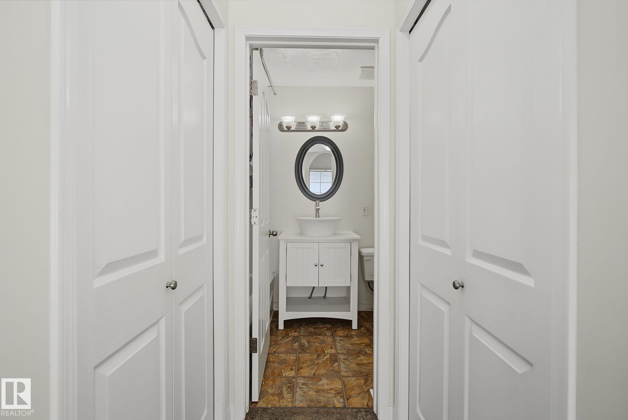 Bathroom featuring a white vanity with vessel sink, oval framed mirror, and three-light fixture - 4259 29 Avenue, Edmonton, AB