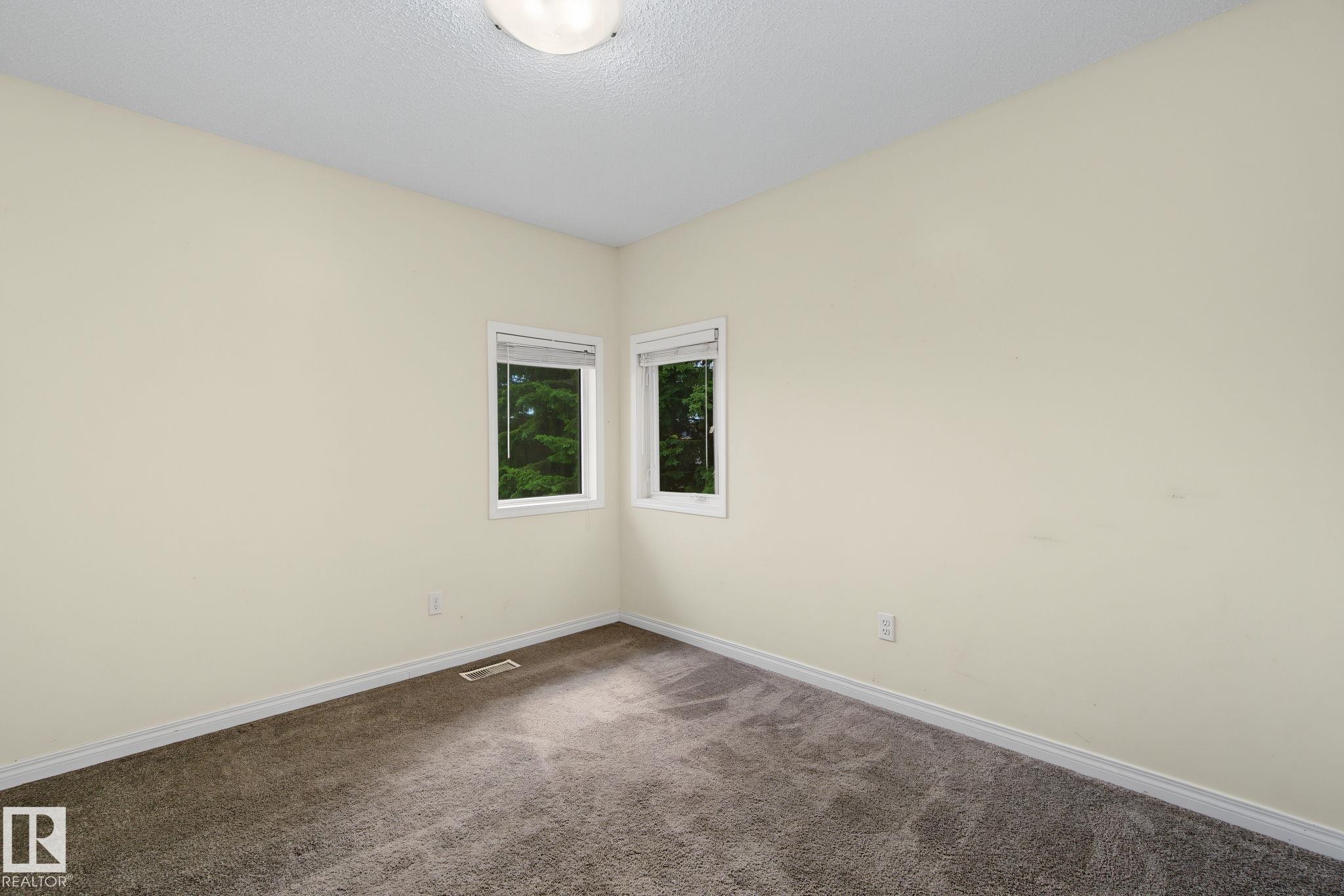 Neutral-toned interior room featuring two windows and plush carpet flooring - 4259 29 Avenue, Edmonton, AB