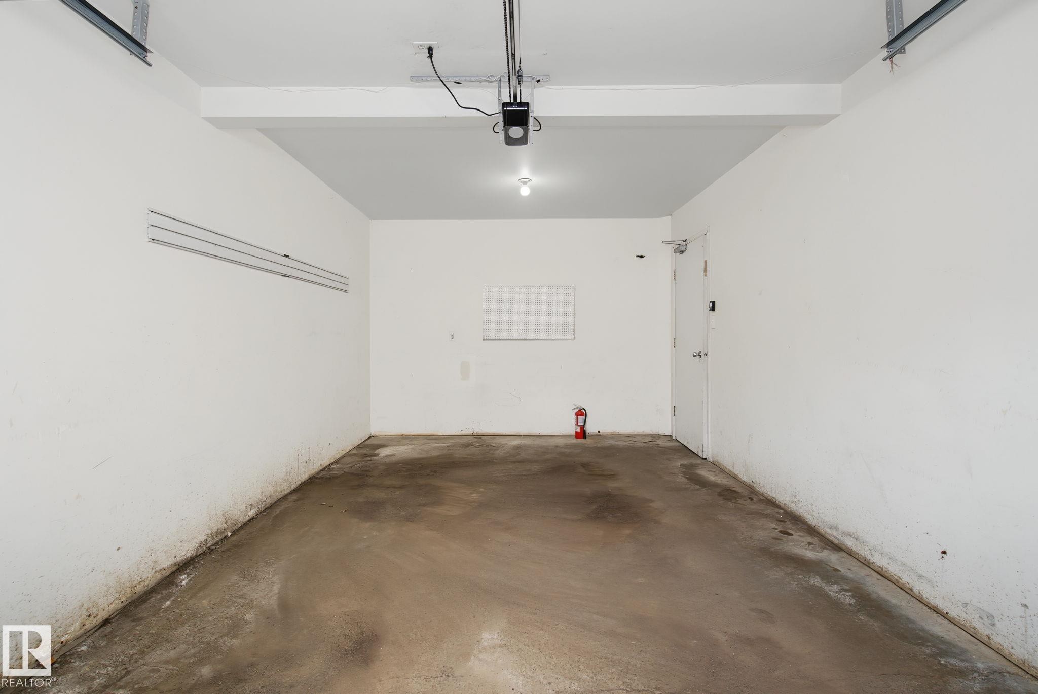 Spacious garage featuring a concrete floor, painted white walls, and a ceiling-mounted garage door opener - 4259 29 Avenue, Edmonton, AB