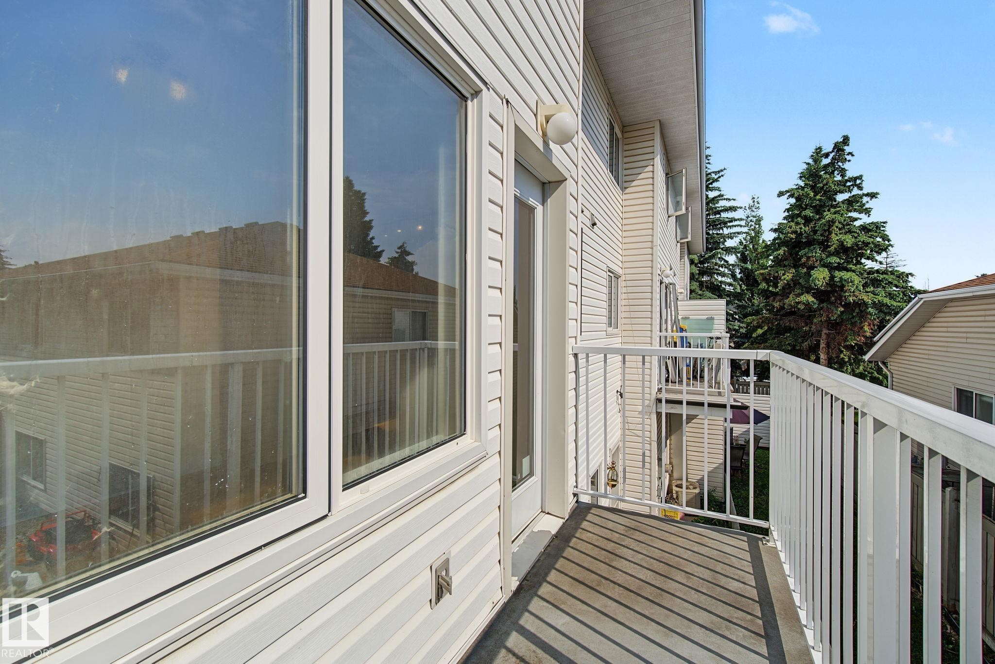 Private balcony with white railing, featuring a large window and exterior lighting fixture - 4259 29 Avenue, Edmonton, AB