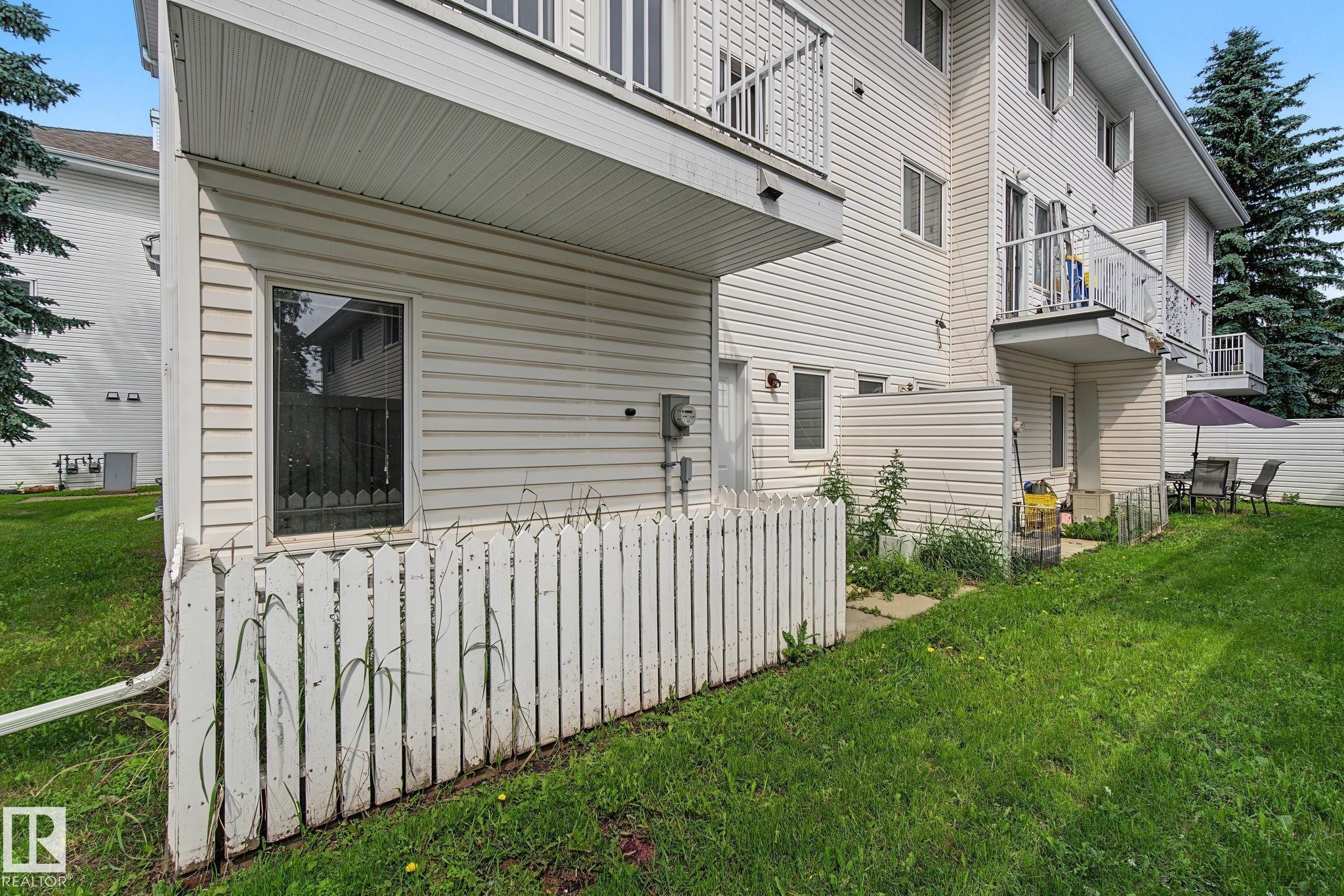 White vinyl siding exterior with a ground-floor window and a white picket fence - 4259 29 Avenue, Edmonton, AB