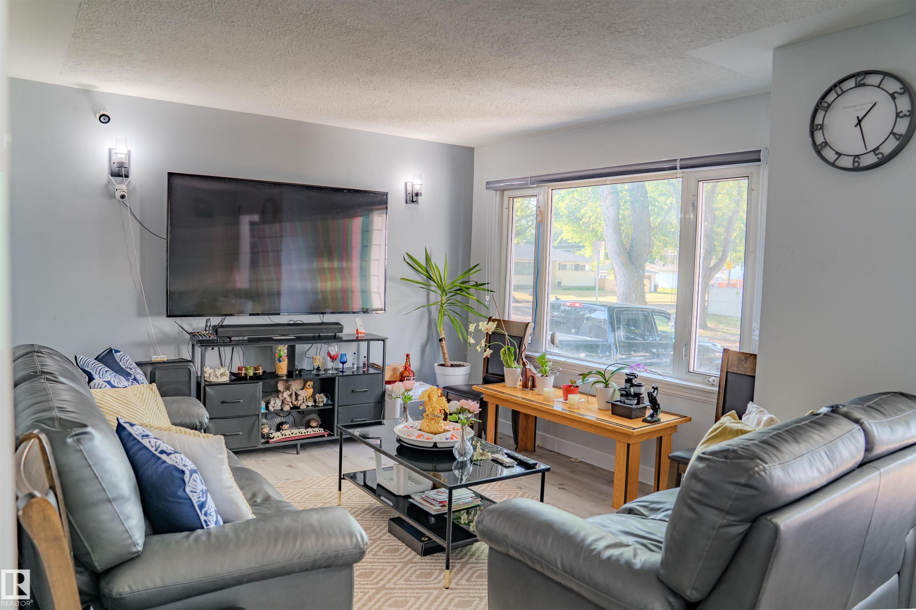 Living area featuring light gray walls, wood-finish flooring, recessed lighting, and a large bay window - 12005 40 St Nw, Edmonton, AB - Indoor Photo Showing Living Room