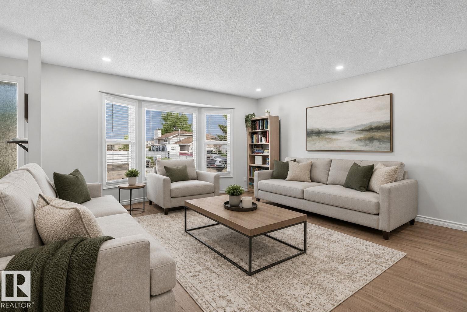 Bright living area featuring a bay window, recessed lighting, wood-finish flooring, and light-toned walls - 3218 41 Street, Leduc, AB