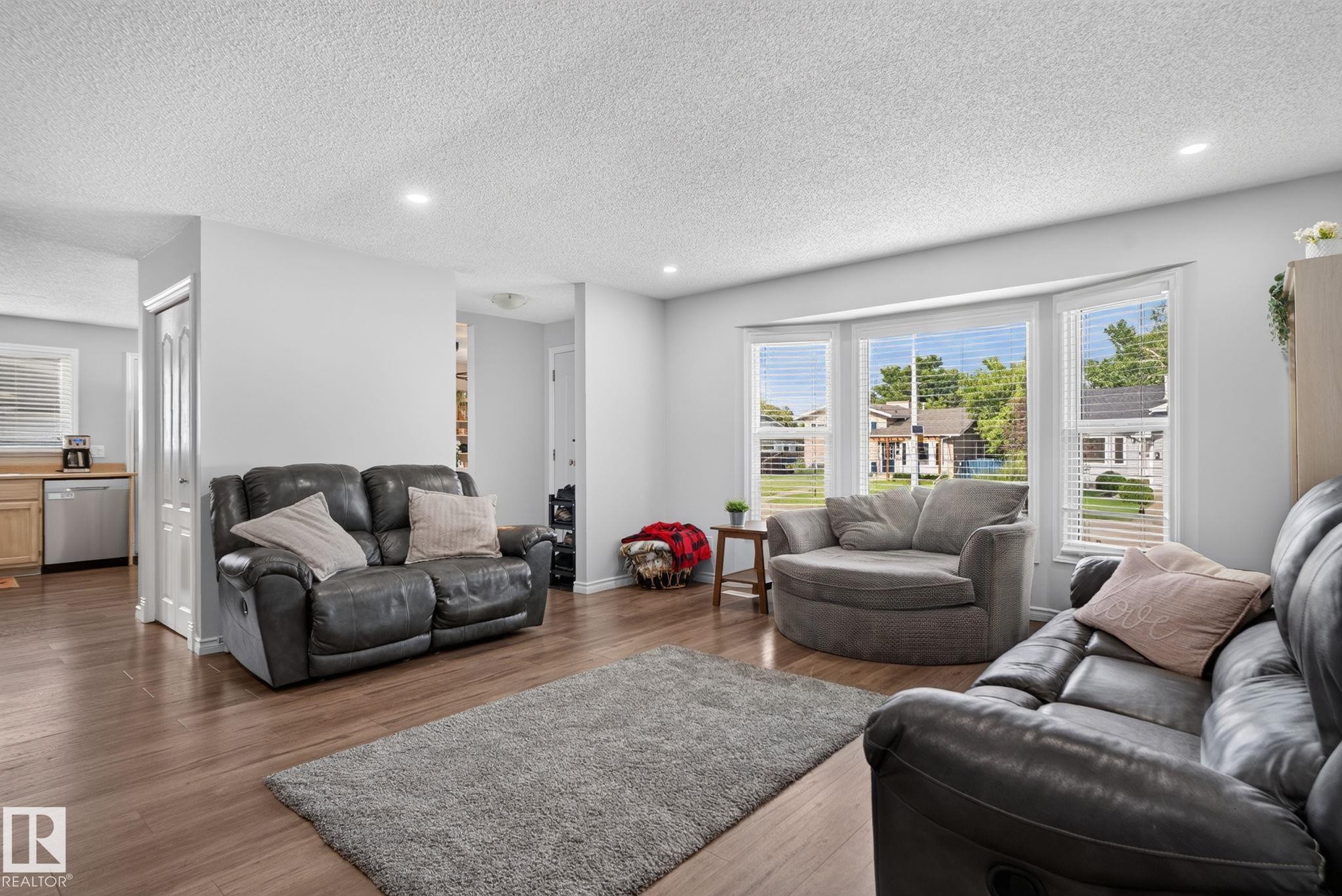 Living area featuring wood-finish flooring, recessed lighting, a bay window with horizontal blinds, and light-toned walls - 3218 41 Street, Leduc, AB