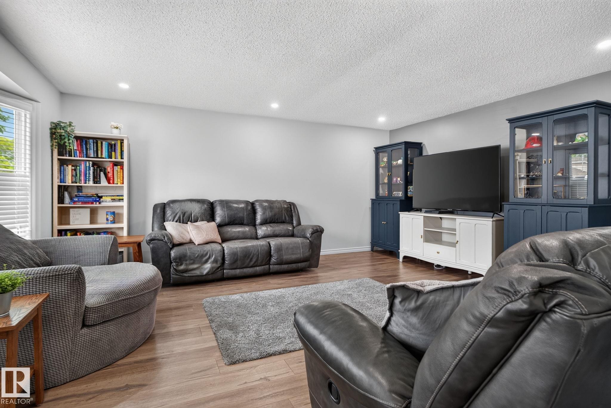 Spacious living area featuring wood-finish flooring, recessed lighting, and light-toned walls - 3218 41 Street, Leduc, AB