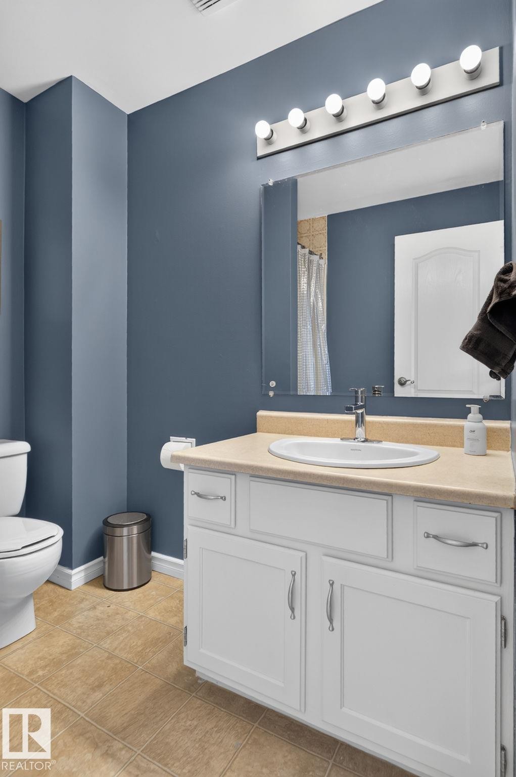 Bathroom featuring a white vanity with brushed nickel hardware, an integrated sink, and a light-toned countertop - 3218 41 Street, Leduc, AB