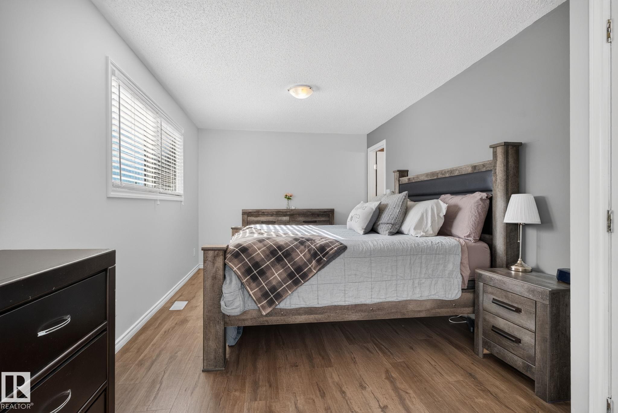 Bedroom featuring wood-finish flooring, light gray wall paint, and white trim - 3218 41 Street, Leduc, AB