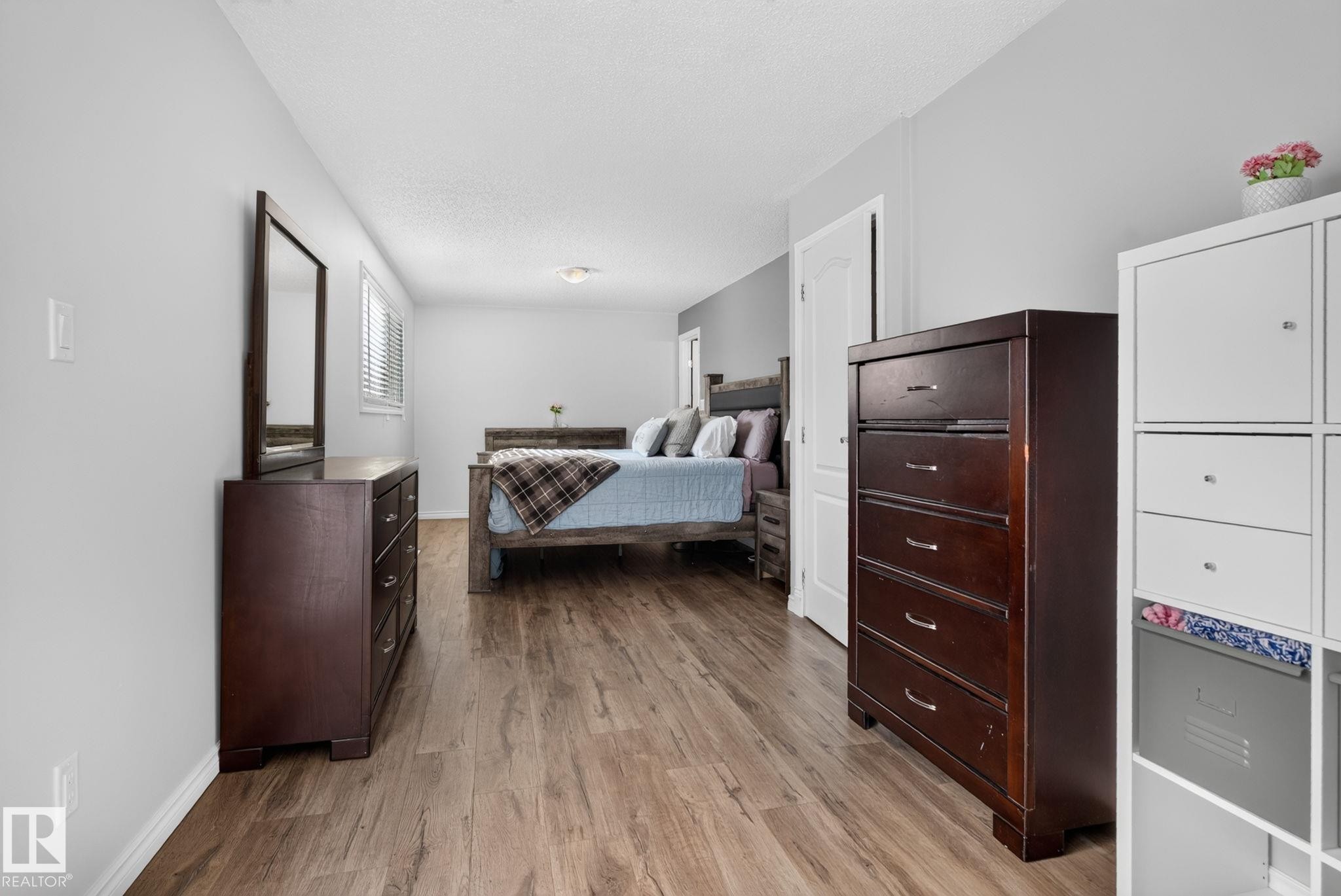 Spacious room with wood-finish flooring, light gray wall paint, and a built-in window with horizontal blinds - 3218 41 Street, Leduc, AB