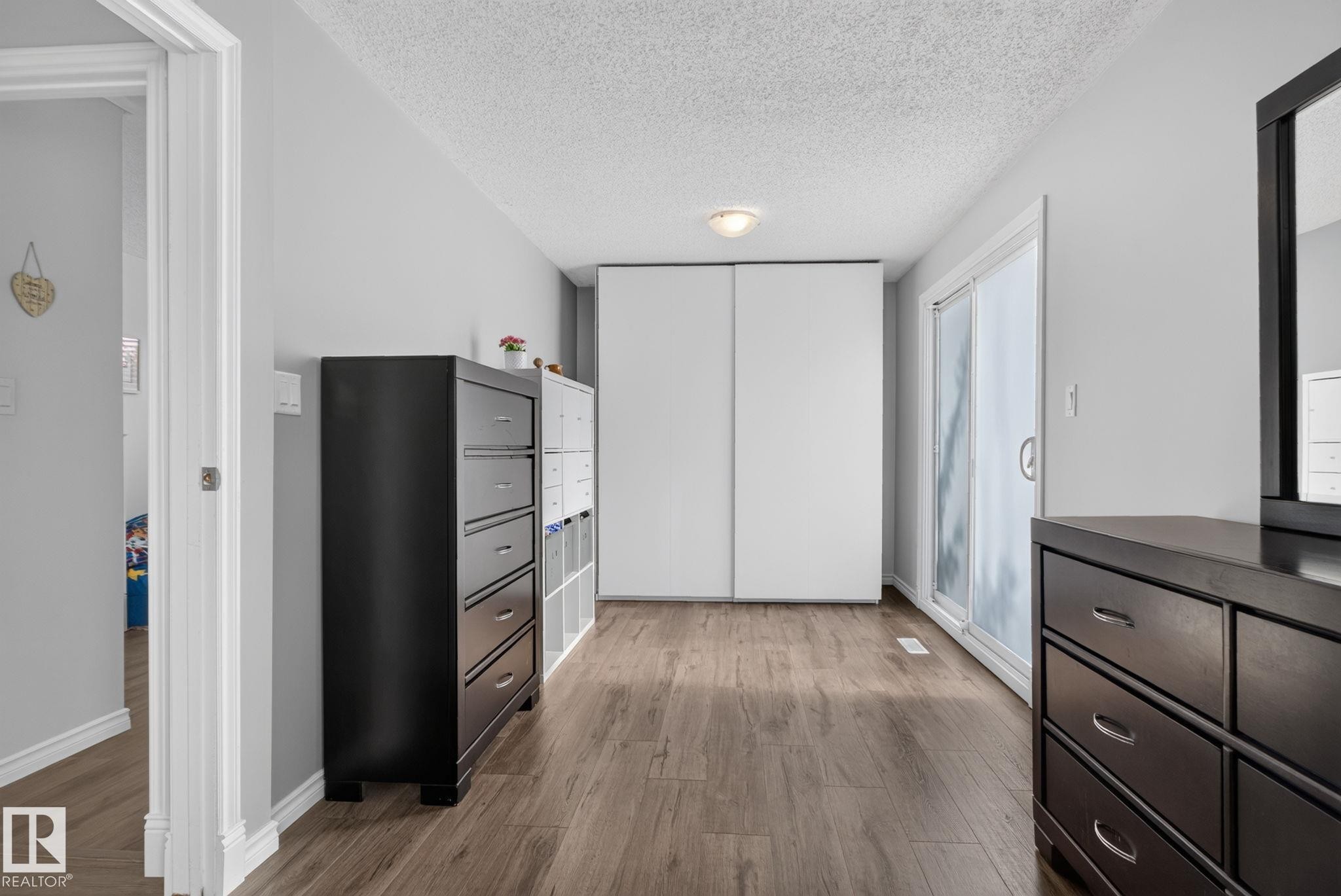 Spacious room featuring wood-finish flooring, light gray walls, and white trim - 3218 41 Street, Leduc, AB