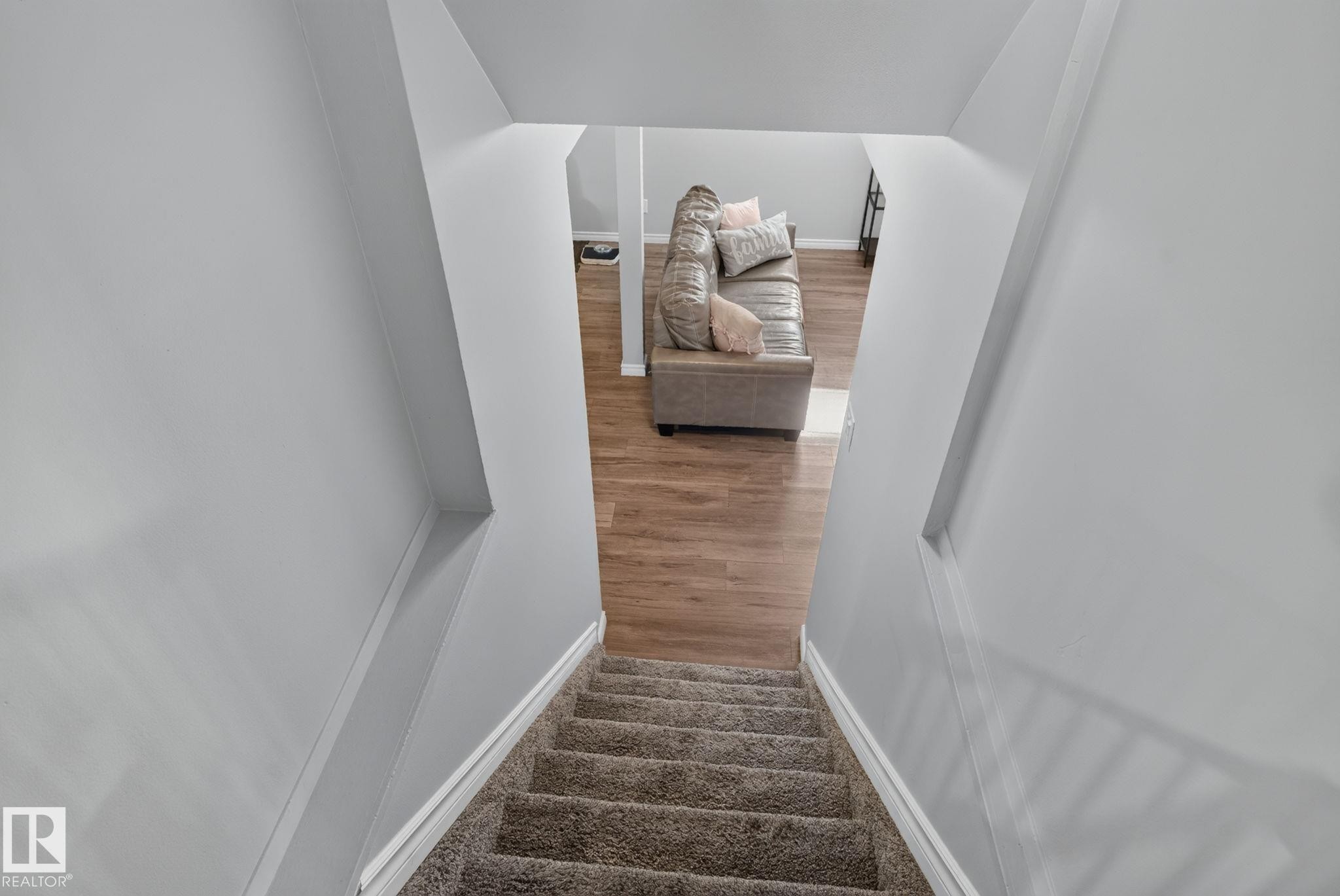 Carpeted staircase descending into a room featuring wood-finish flooring and light gray walls - 3218 41 Street, Leduc, AB