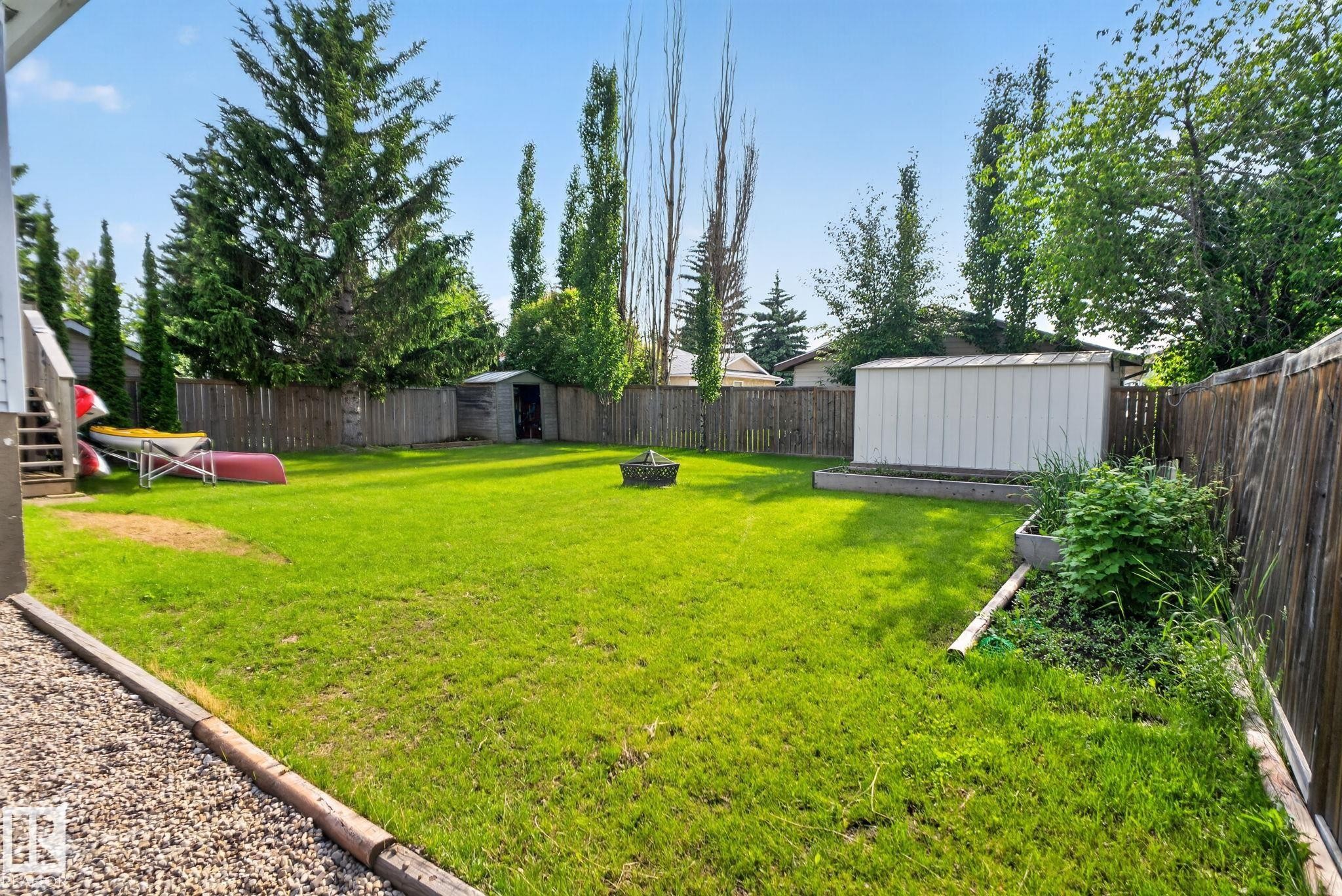 Spacious backyard featuring a manicured lawn, established perimeter fencing, and mature trees - 3218 41 Street, Leduc, AB