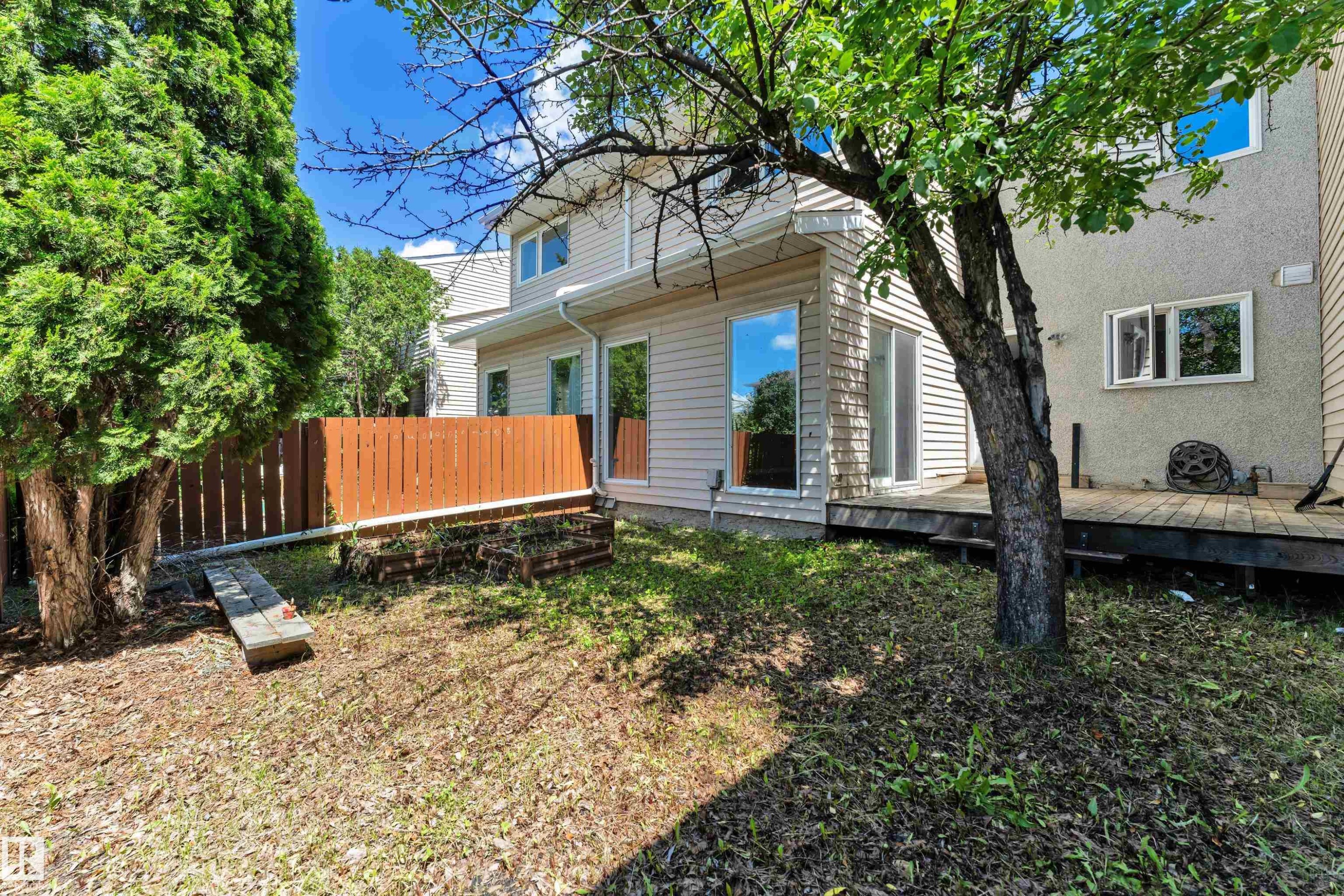 Expansive backyard featuring a wood deck, mature trees, and a privacy fence - 6632 36A Avenue, Edmonton, AB