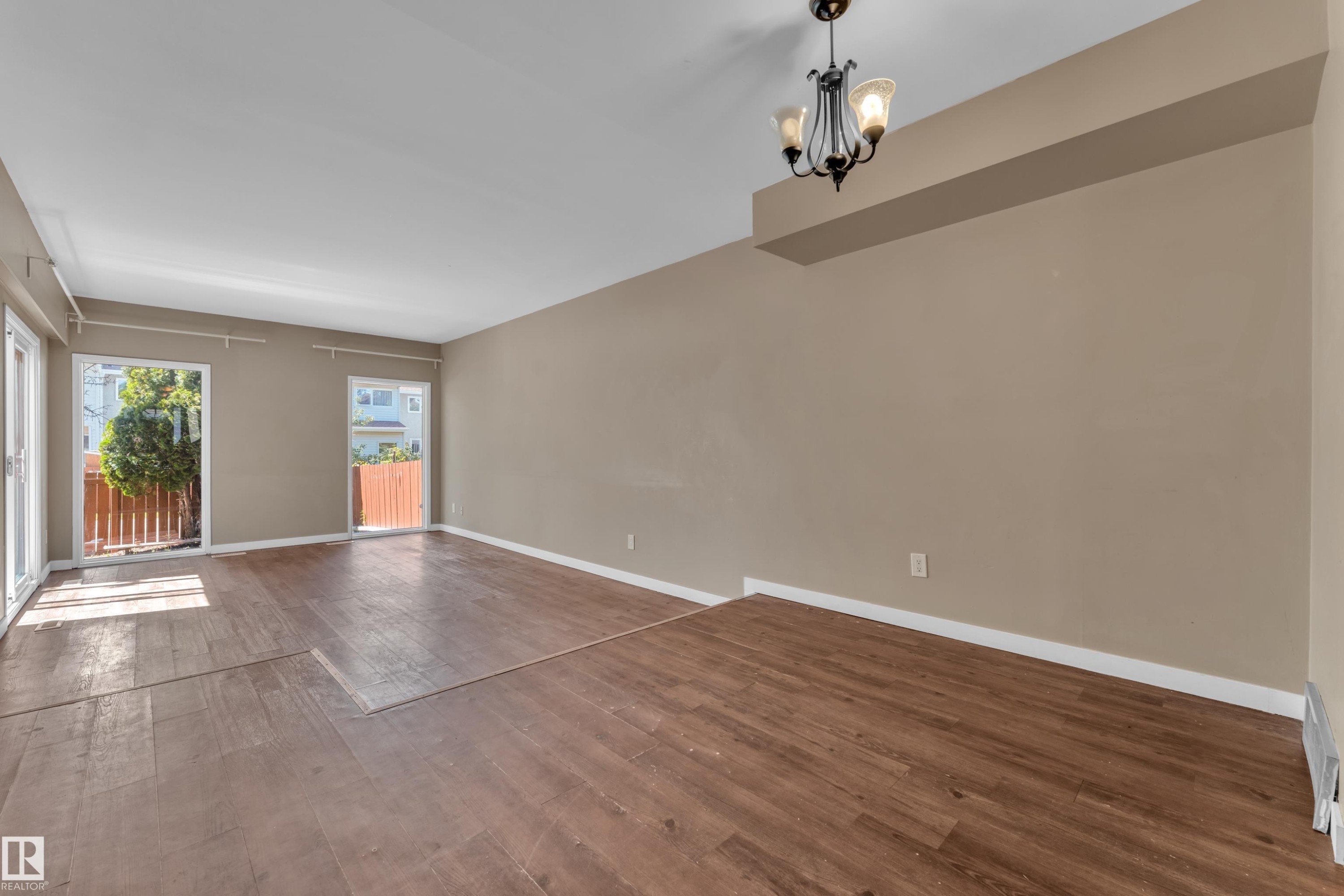 Spacious room featuring wood-finish flooring, neutral-toned walls, and recessed lighting - 6632 36A Avenue, Edmonton, AB
