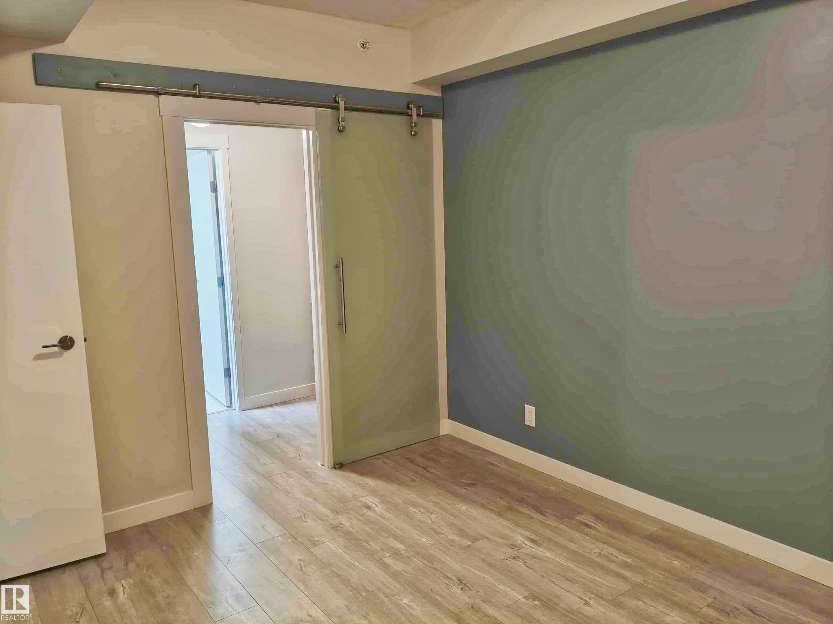 Wood-finish flooring throughout - #2505 10410 102 Av Nw, Edmonton, AB - Indoor Photo Showing Other Room