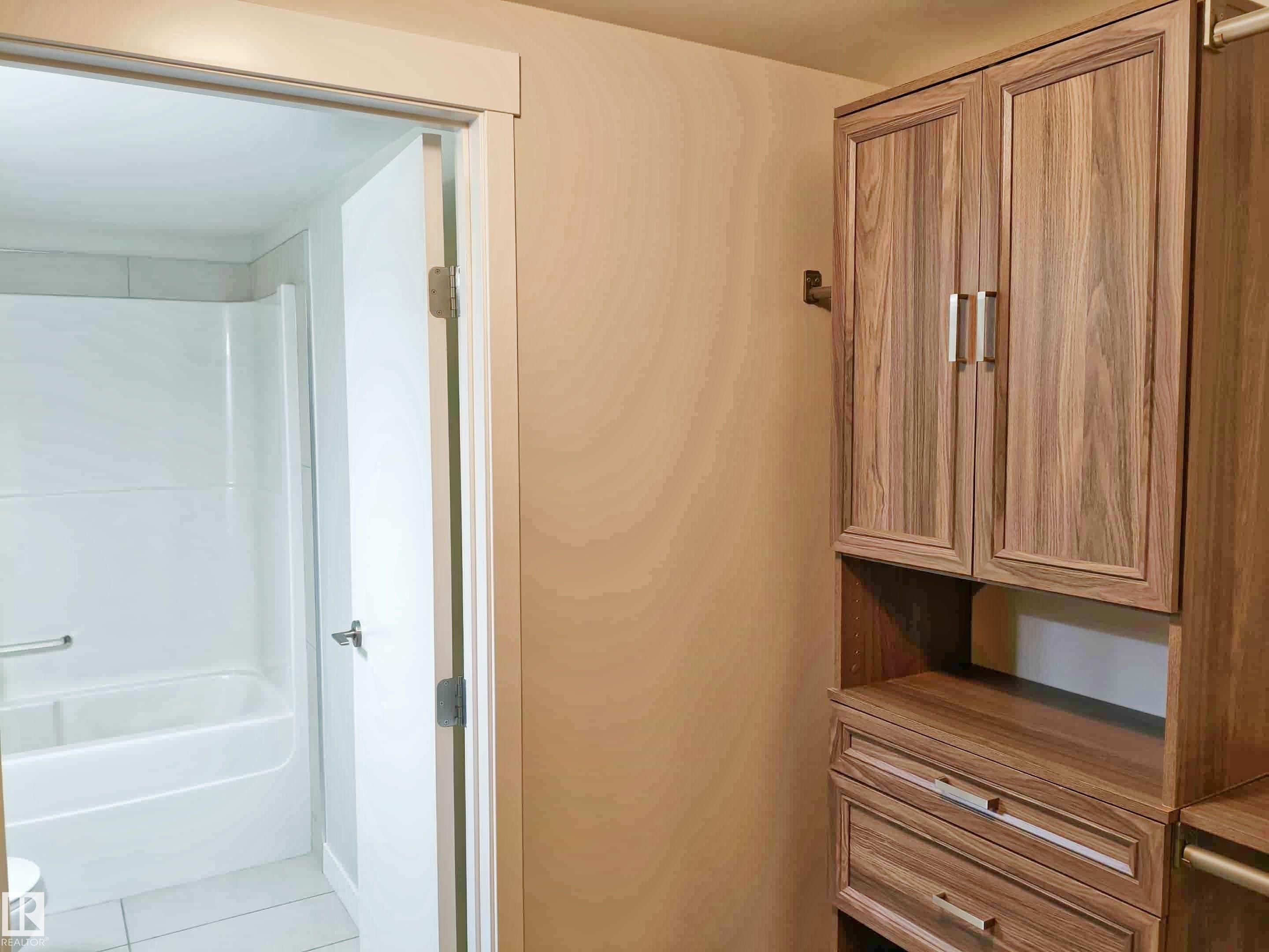 Custom built-in storage system with wood-finish cabinetry and brushed nickel hardware - #2505 10410 102 Av Nw, Edmonton, AB - Indoor Photo Showing Bathroom