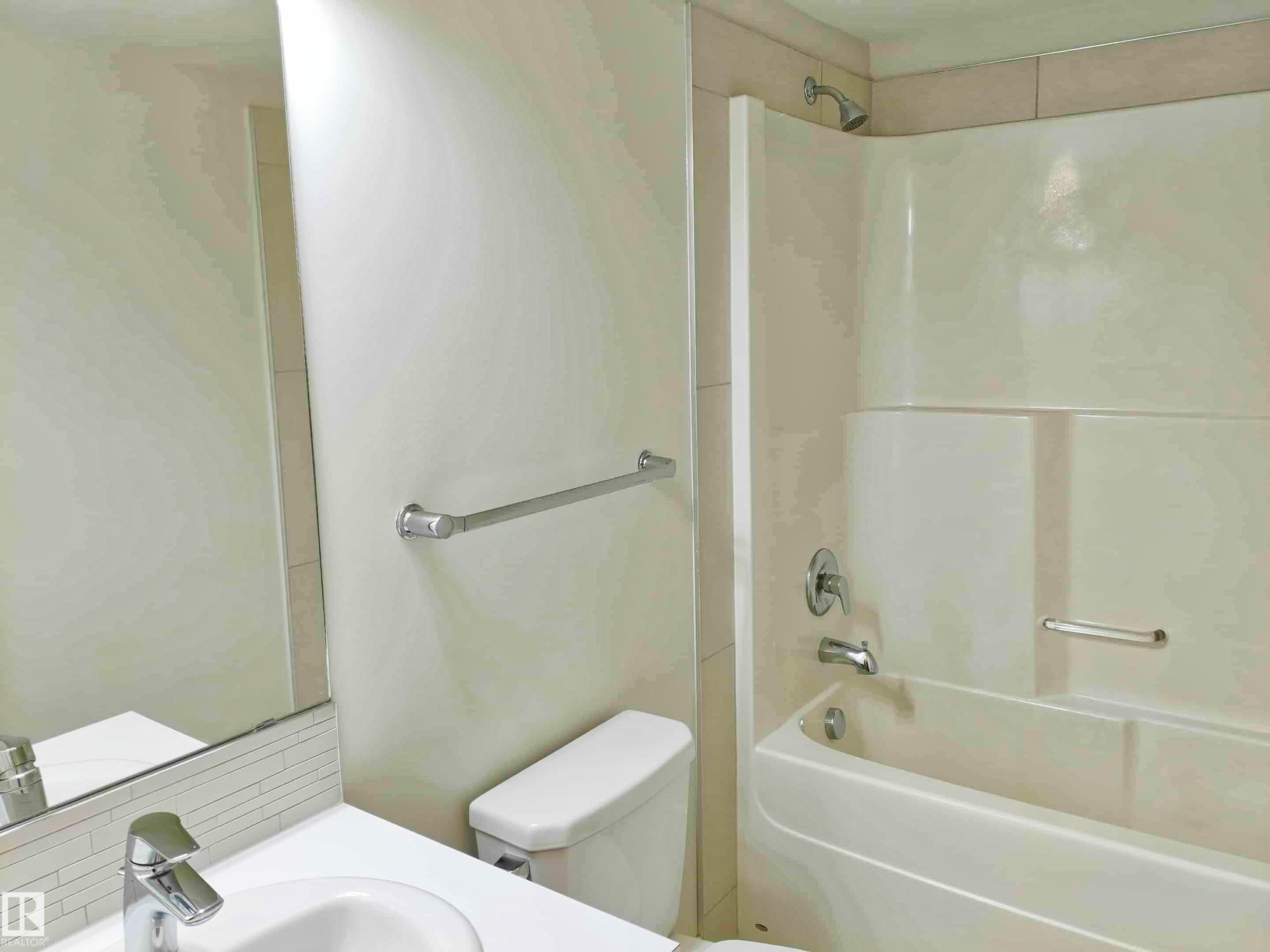 Bathroom featuring a white vanity with an integrated sink, chrome faucet, and a subway tile backsplash - #2505 10410 102 Av Nw, Edmonton, AB - Indoor Photo Showing Bathroom