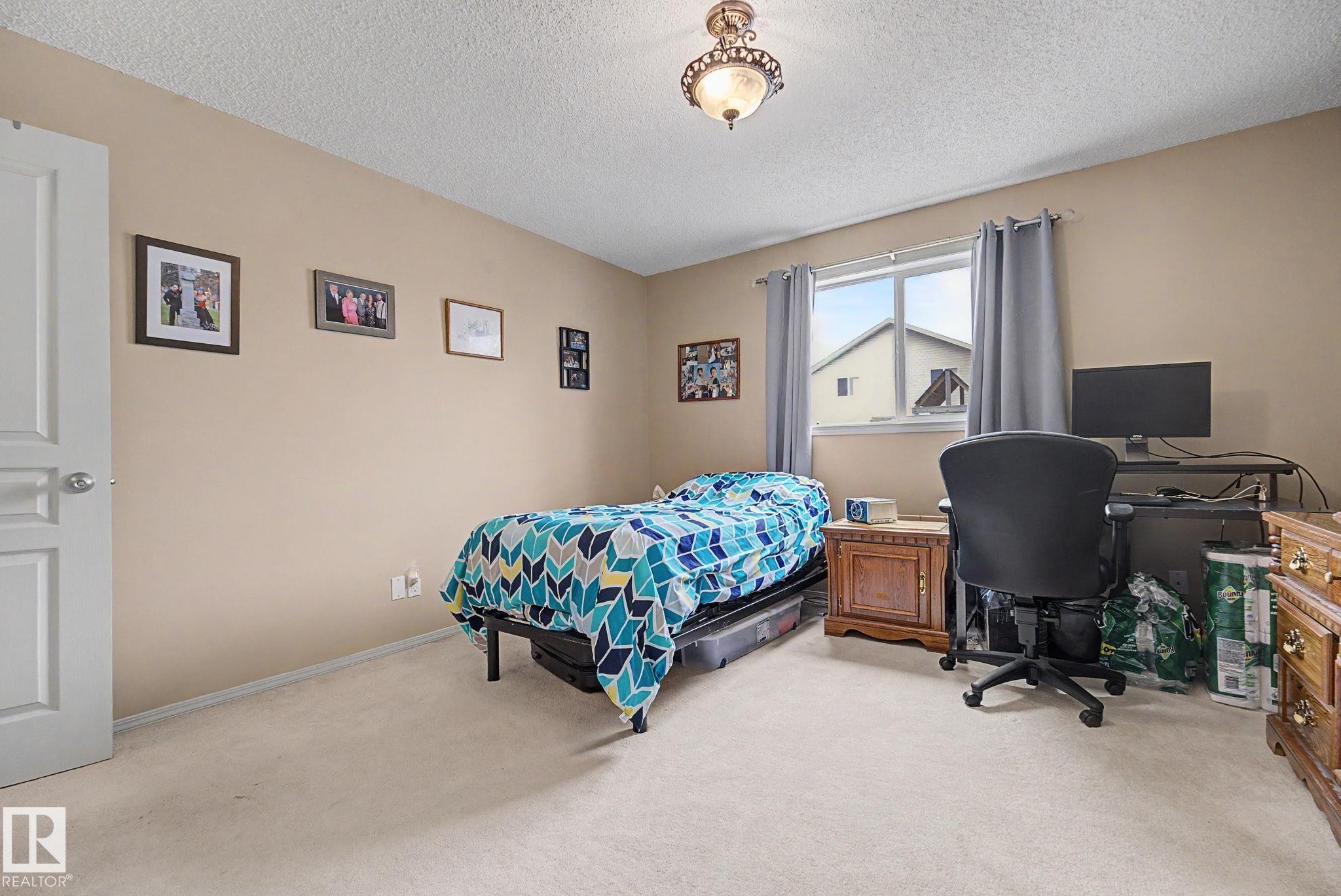 Carpeted room featuring a single window with curtain rods, a ceiling-mounted light fixture, and a solid white door - 19039 47 Avenue Nw, Edmonton, AB - Indoor Photo Showing Bedroom