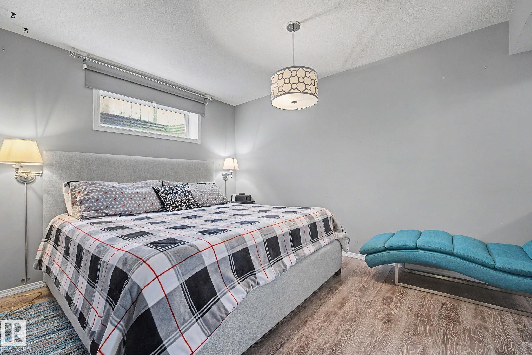 Bedroom featuring wood-finish flooring, light gray walls, and an upholstered headboard - 19039 47 Avenue Nw, Edmonton, AB - Indoor Photo Showing Bedroom