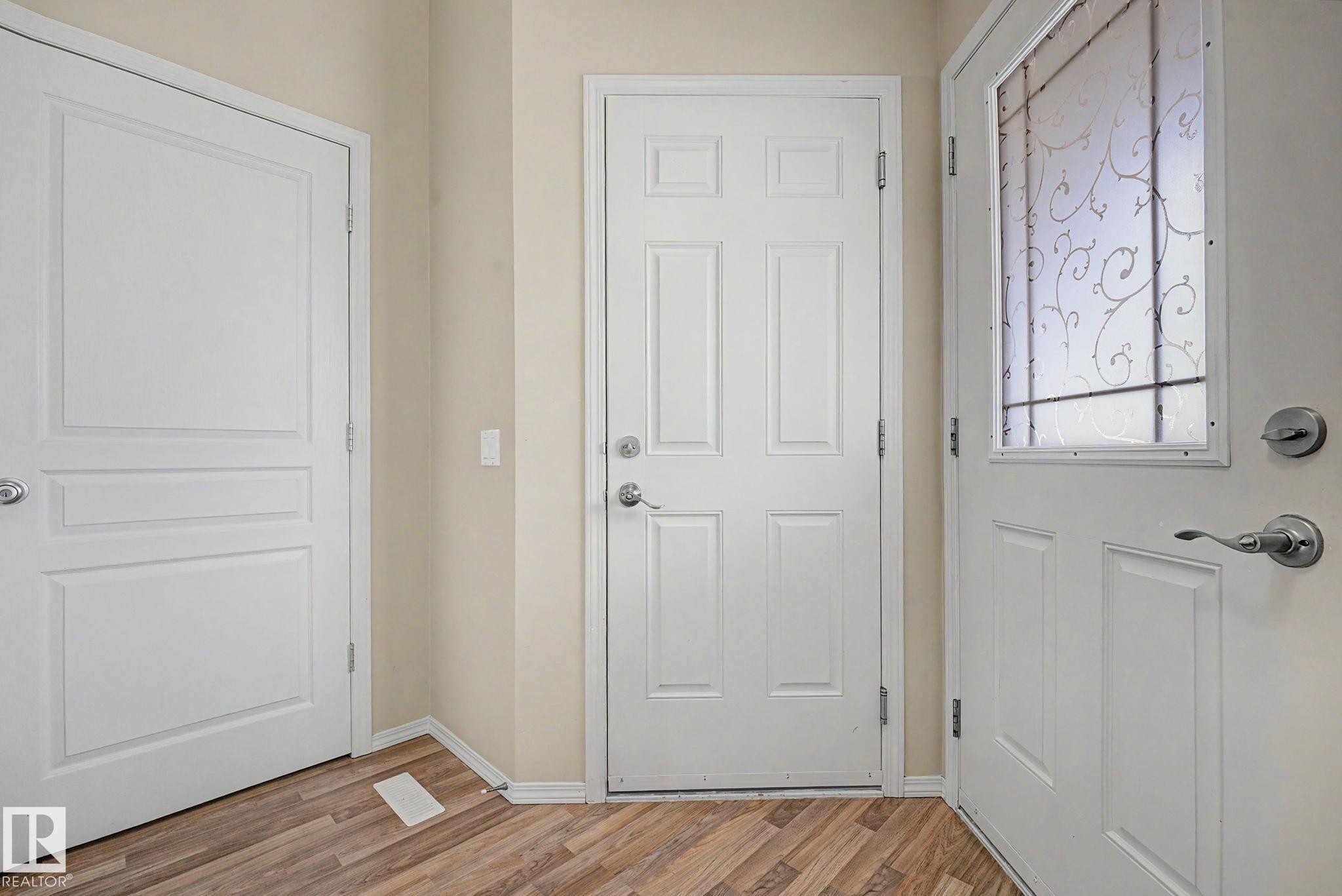 Entryway featuring a decorative glass panel door, wood-finish flooring, and white trim - 19039 47 Avenue Nw, Edmonton, AB - Indoor Photo Showing Other Room