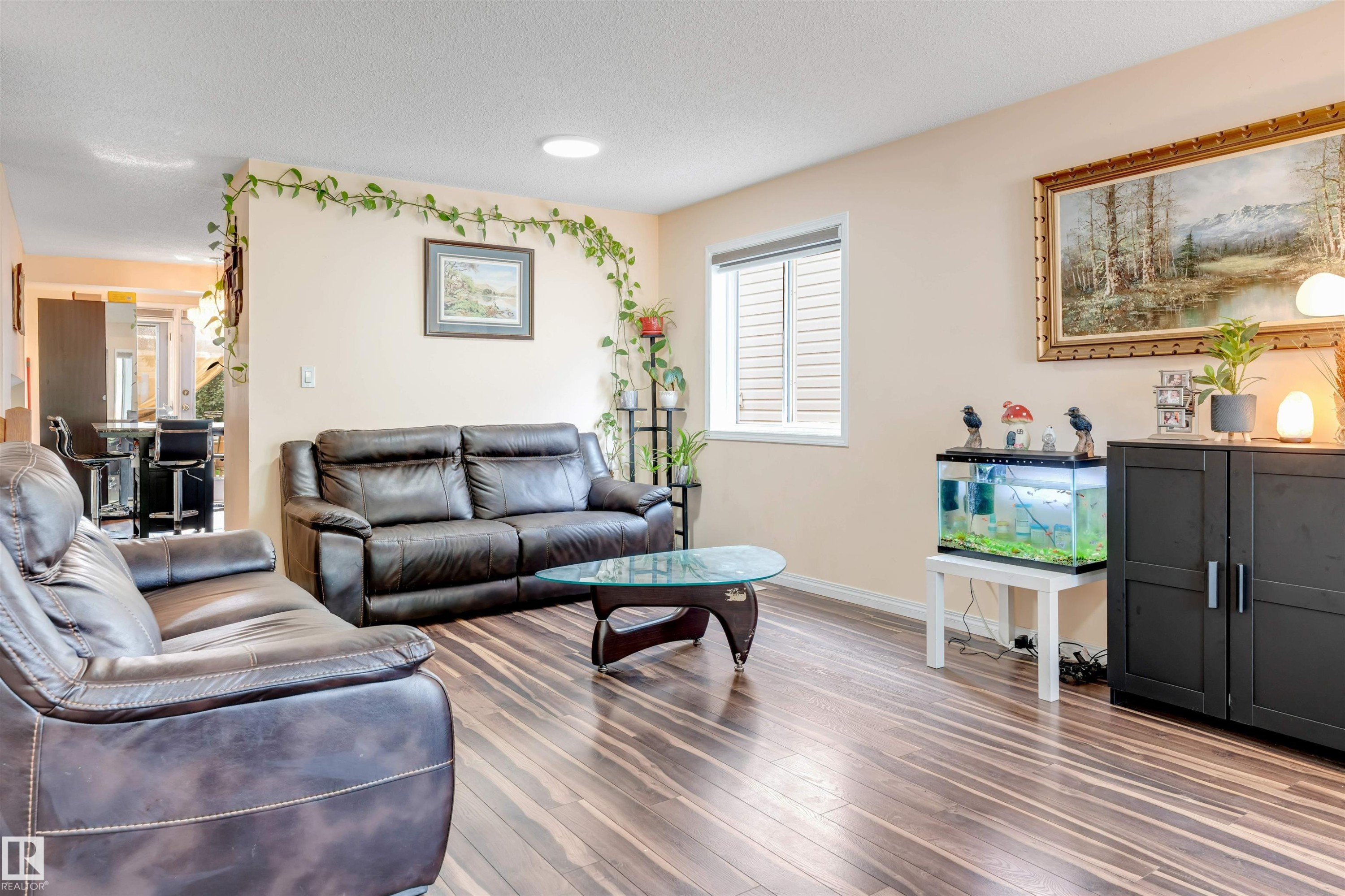 Open-concept living area featuring wood-finish flooring, a white-framed window with horizontal blinds, and a built-in ceiling light fixture - 312 Beringer Crescent Nw, Edmonton, AB - Indoor Photo Showing Living Room