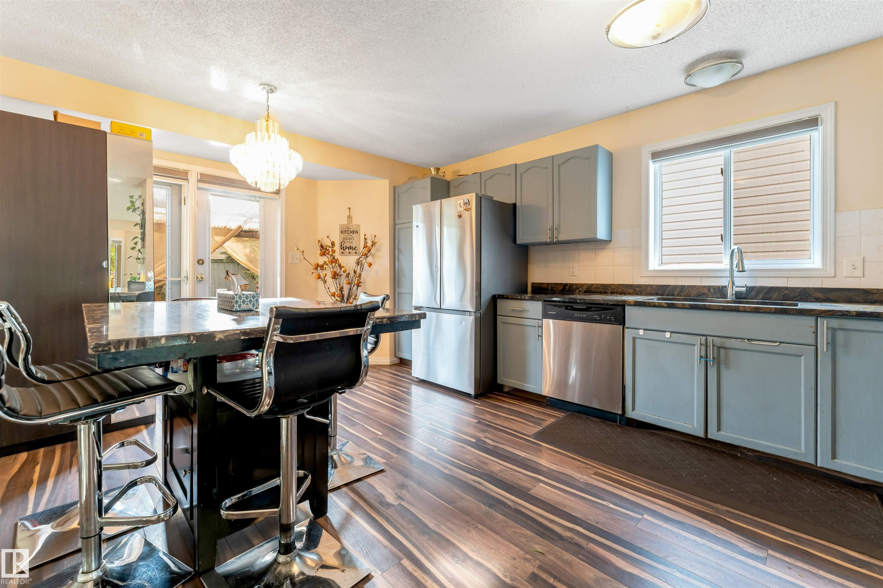 Kitchen featuring wood-finish flooring, light grey cabinetry, dark countertops, and stainless steel appliances - 312 Beringer Crescent Nw, Edmonton, AB - Indoor