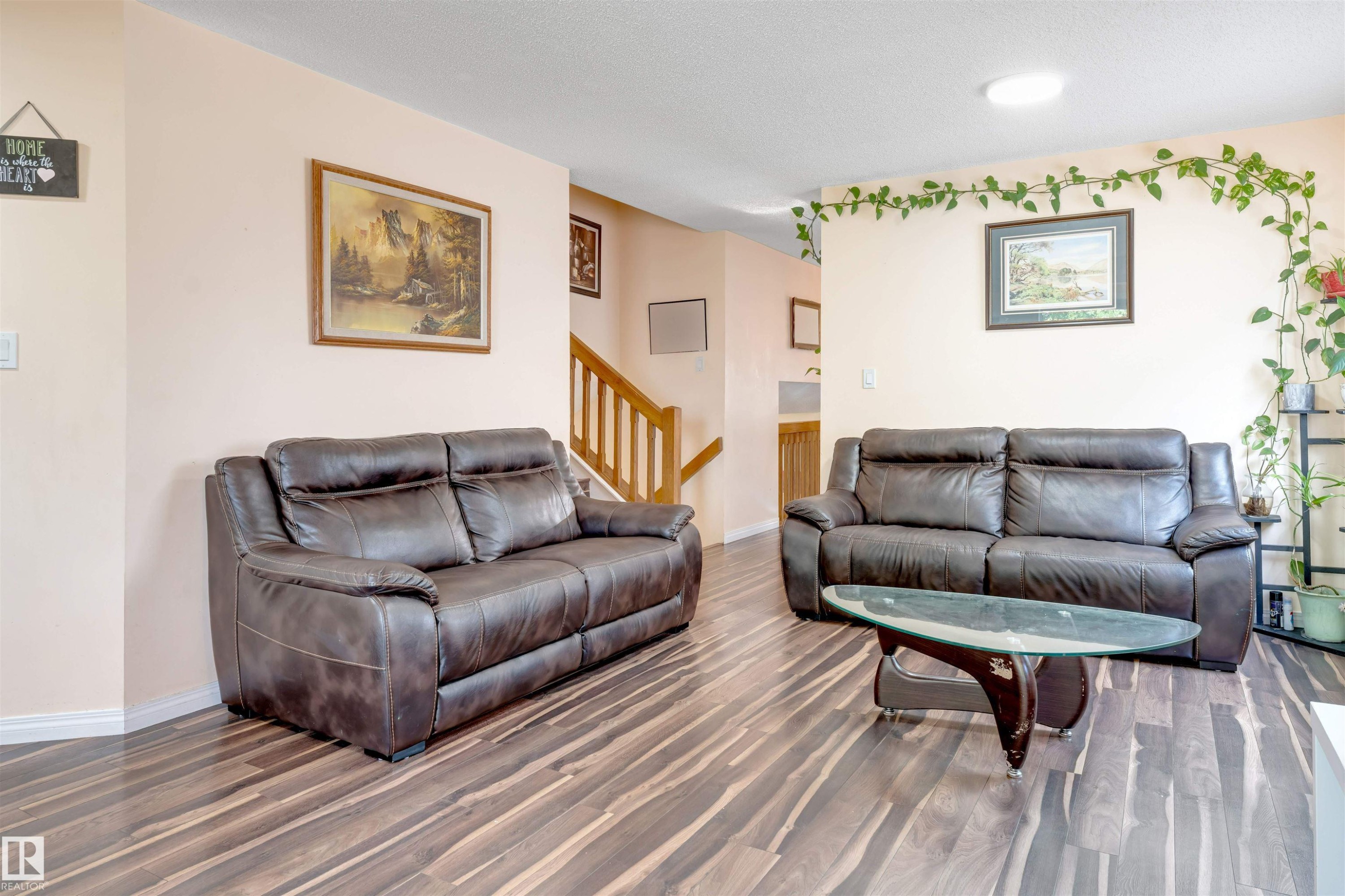 Open-concept living area featuring wood-finish flooring, light-toned walls, and a built-in staircase with wood railings - 312 Beringer Crescent Nw, Edmonton, AB - Indoor Photo Showing Living Room