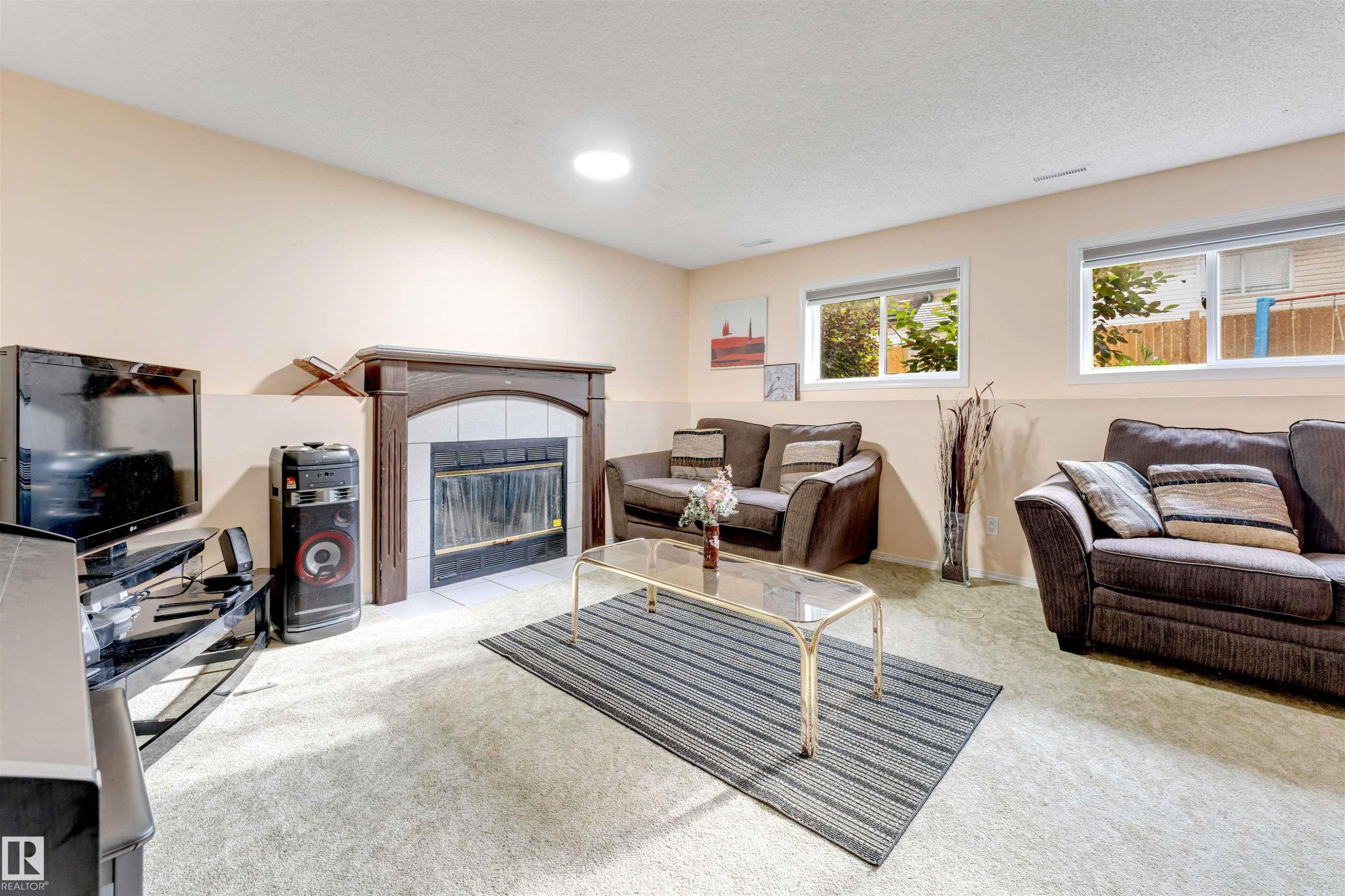 Living area featuring a dark wood mantel fireplace with a tiled surround, two windows, and light-colored carpeting - 312 Beringer Crescent Nw, Edmonton, AB - Indoor With Fireplace