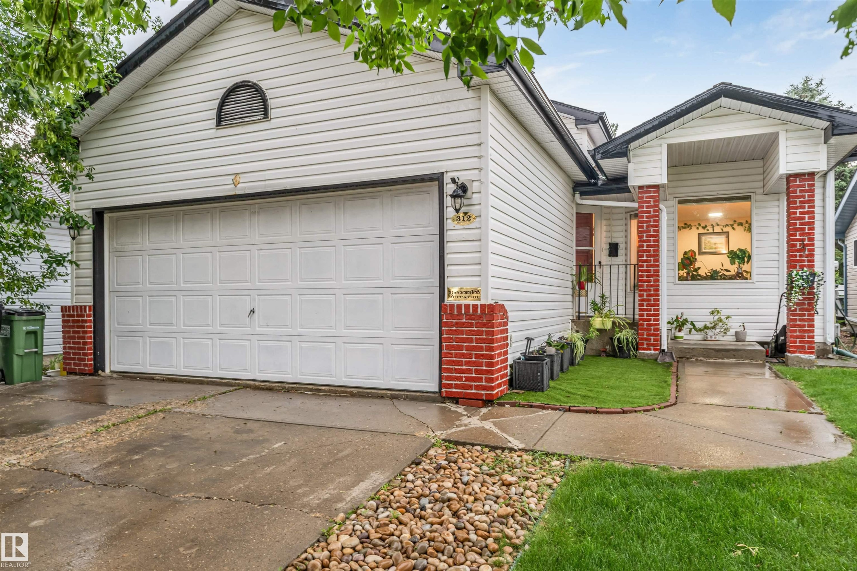 White vinyl siding exterior with an attached garage, brick accents, and a covered entry - 312 Beringer Crescent Nw, Edmonton, AB - Outdoor