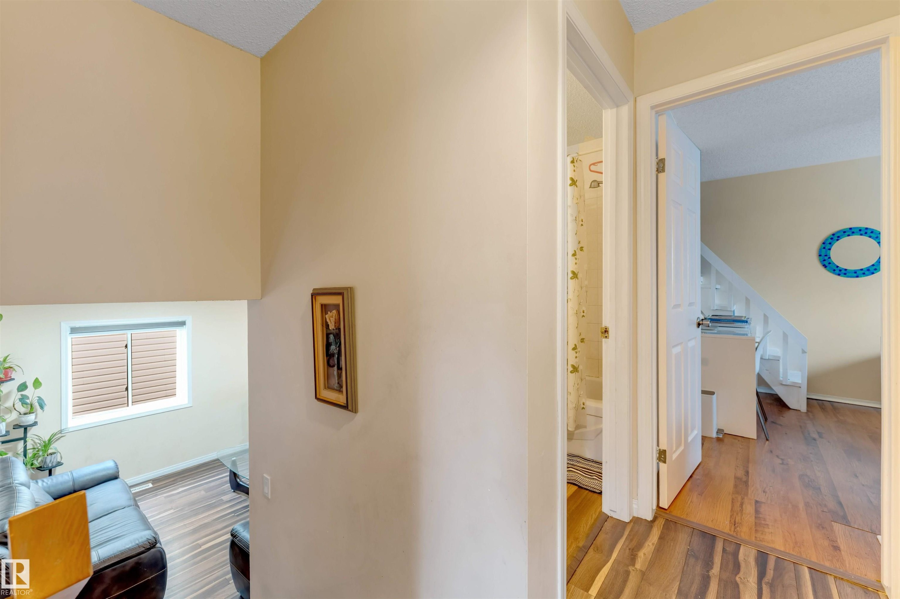 Hallway featuring wood-finish flooring, two white panel doors, and neutral wall paint - 312 Beringer Crescent Nw, Edmonton, AB - Indoor