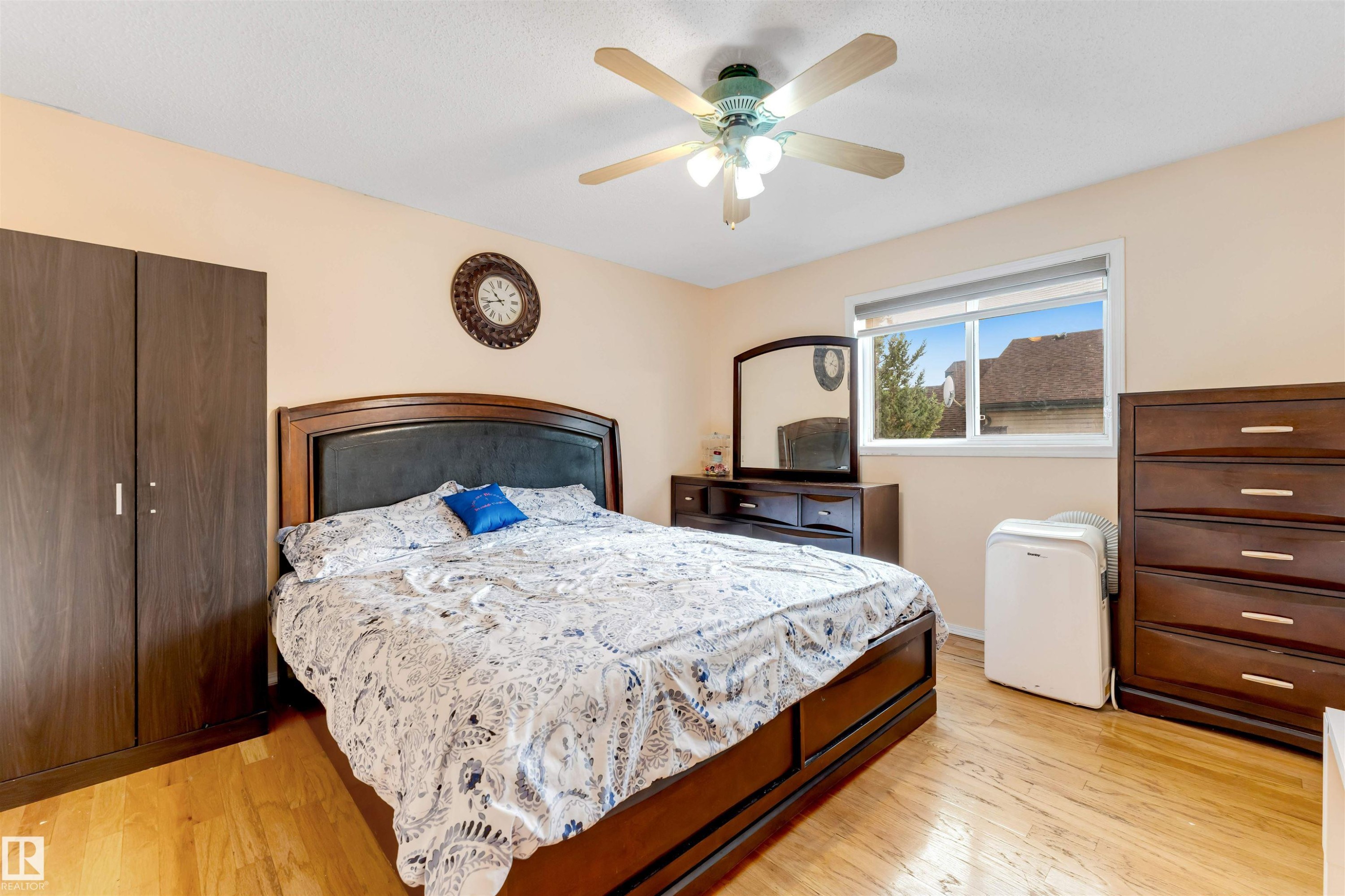 Spacious room featuring wood-finish flooring, a window offering natural illumination, and a ceiling fan with integrated lighting - 312 Beringer Crescent Nw, Edmonton, AB - Indoor Photo Showing Bedroom
