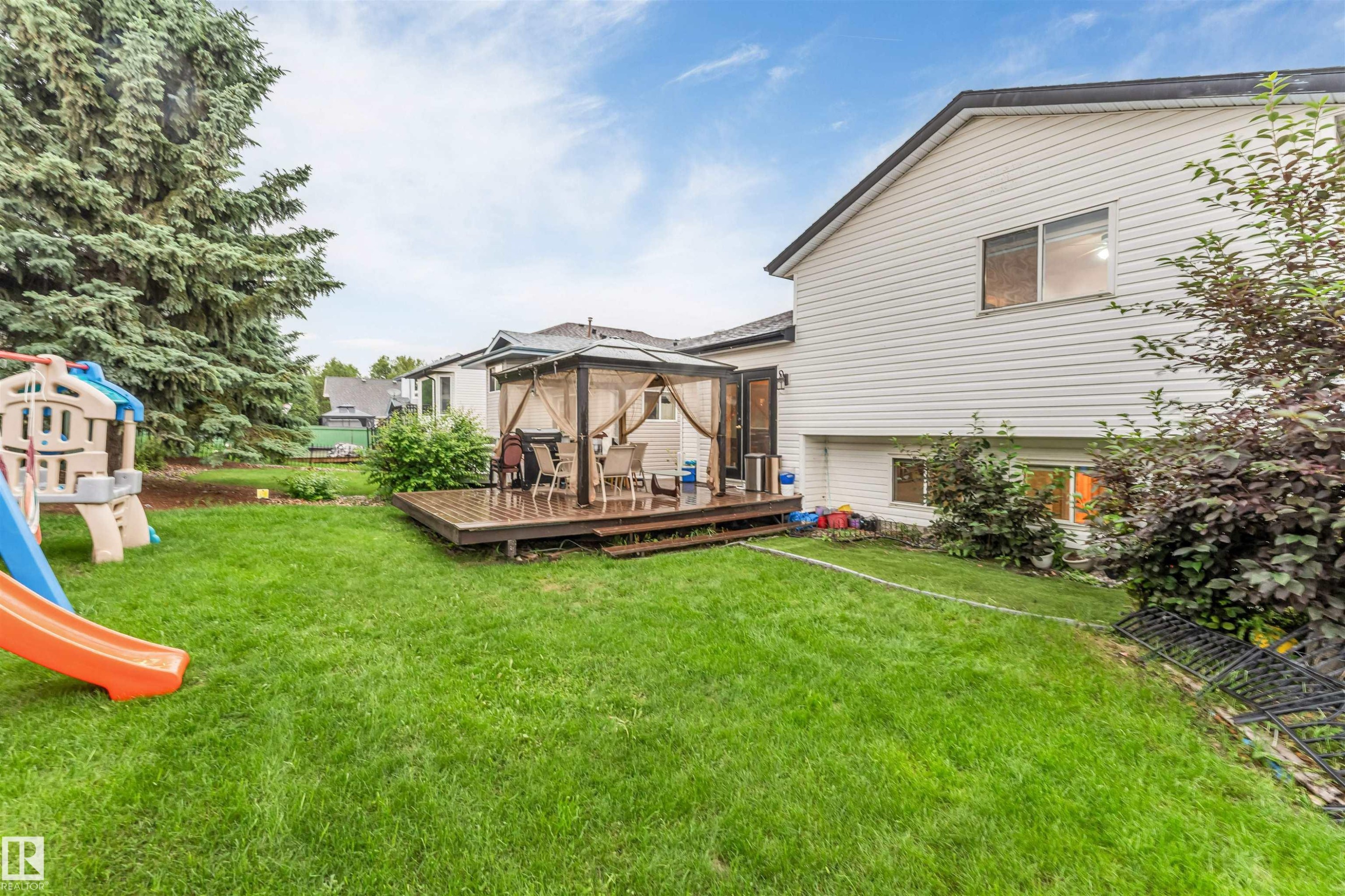 Expansive backyard featuring a large wood deck with a gazebo, mature evergreen trees, and a manicured lawn - 312 Beringer Crescent Nw, Edmonton, AB - Outdoor With Deck Patio Veranda