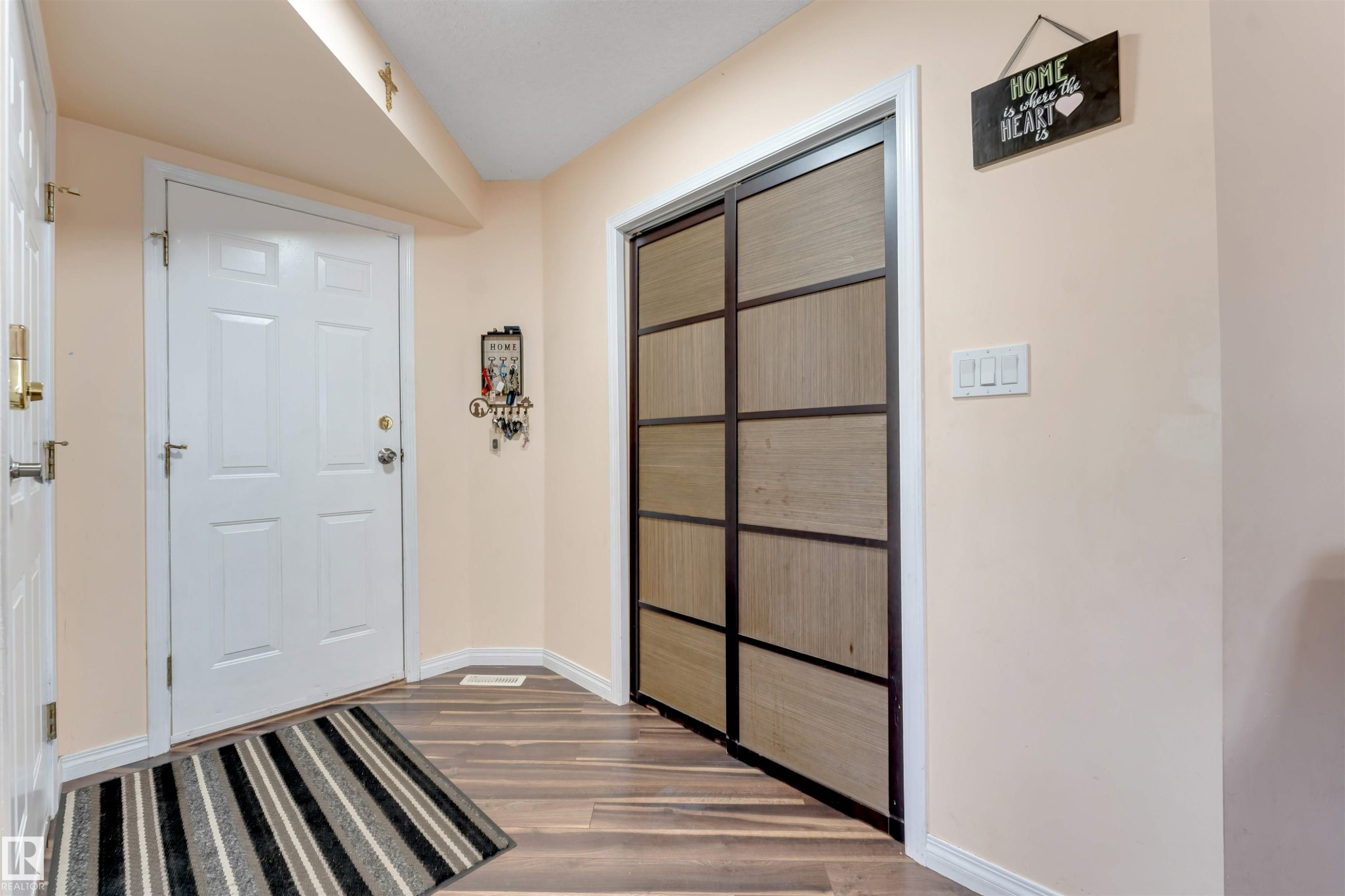 Entryway featuring wood-finish flooring, a white paneled entry door, and a built-in closet with sliding wood-paneled doors - 312 Beringer Crescent Nw, Edmonton, AB - Indoor Photo Showing Other Room