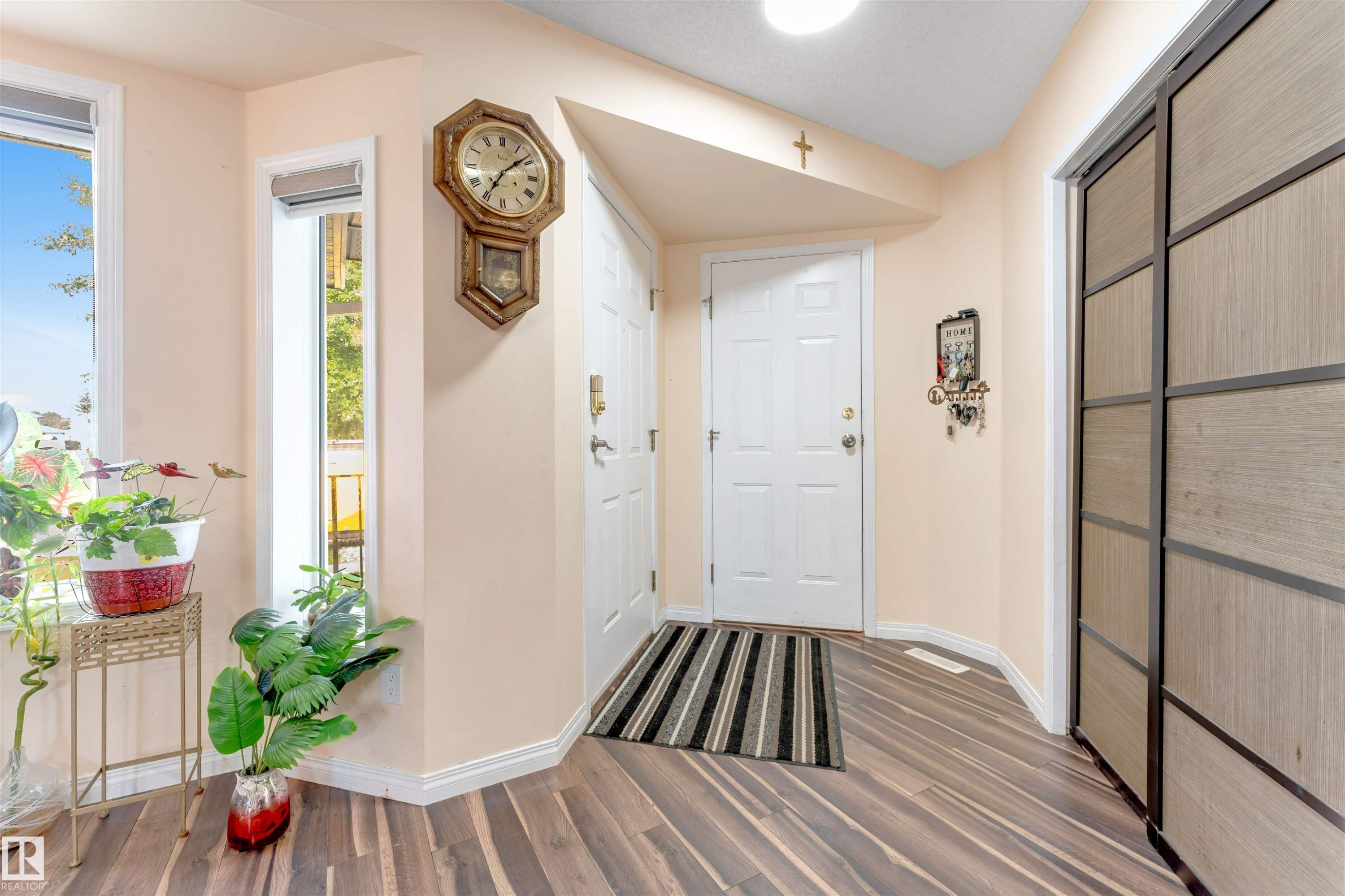 Entryway featuring wood-finish flooring, white paneled doors, and a built-in closet with sliding panel doors - 312 Beringer Crescent Nw, Edmonton, AB - Indoor Photo Showing Other Room