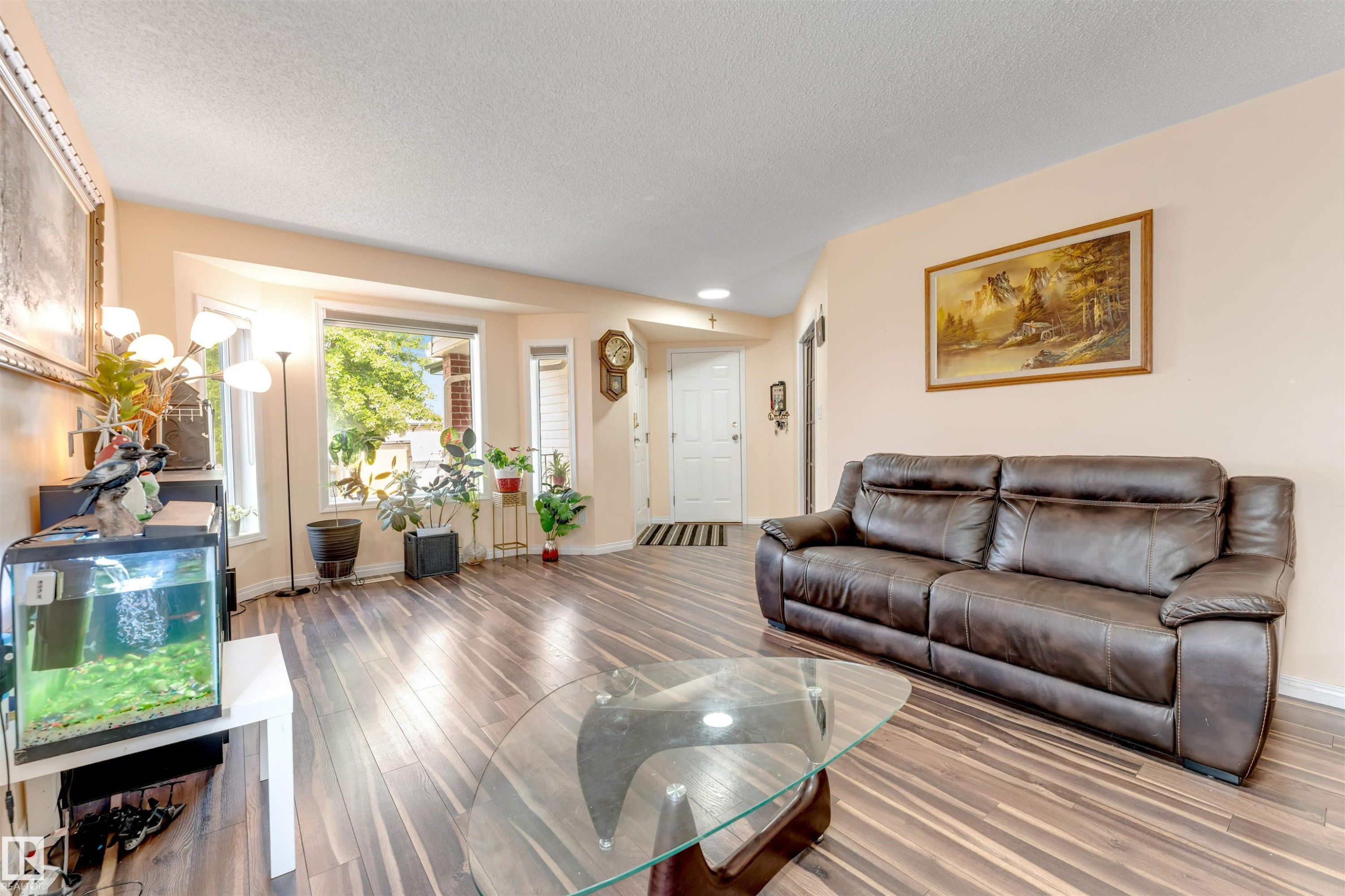 Spacious living area featuring wood-finish flooring, a bright bay window, and a white entry door - 312 Beringer Crescent Nw, Edmonton, AB - Indoor Photo Showing Living Room