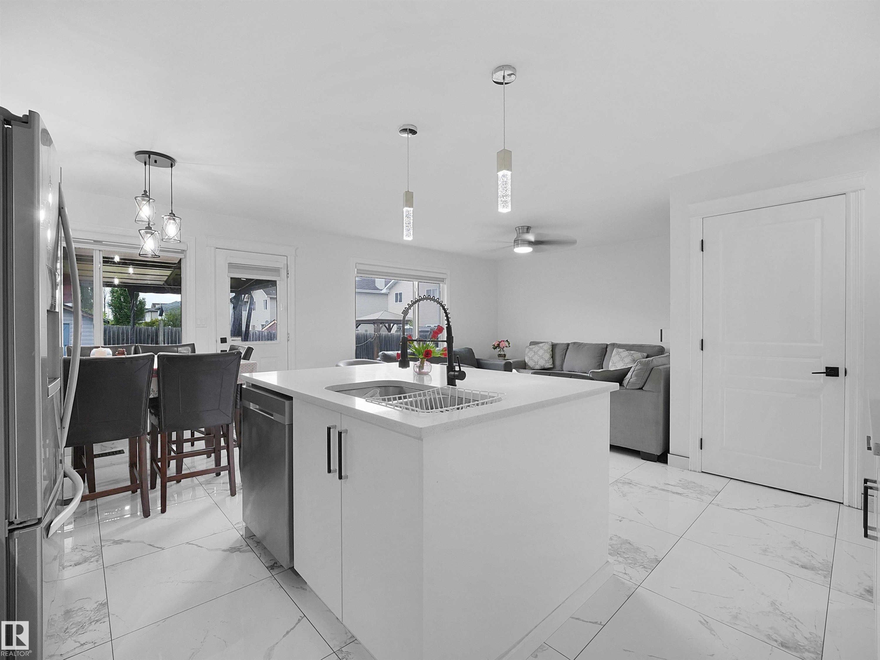 Contemporary kitchen island with a white solid surface countertop, undermount sink, and black matte faucet - 2418 32B Street, Edmonton, AB