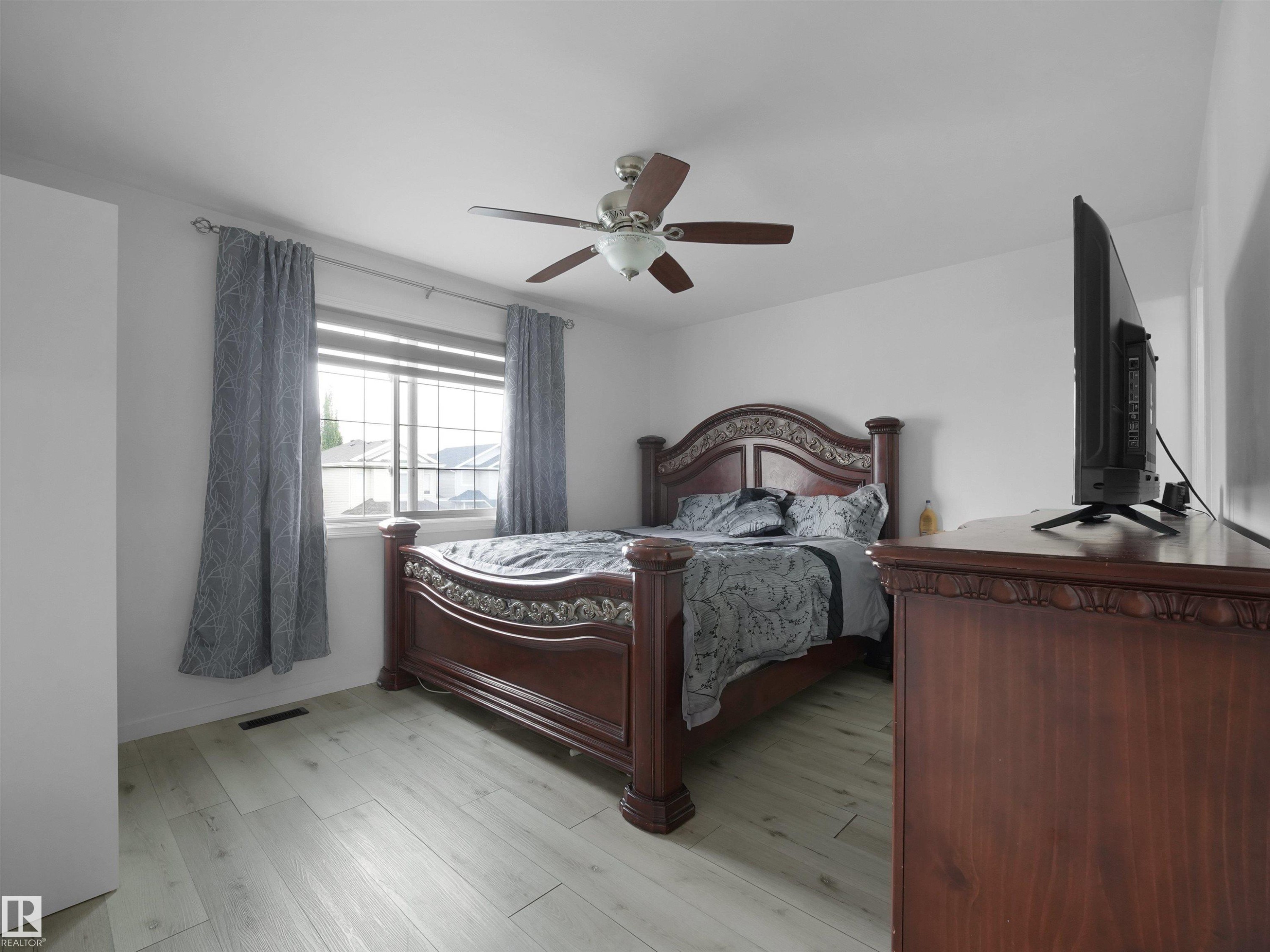 Bright room featuring light wood-finish flooring and a window with blinds and curtains - 2418 32B Street, Edmonton, AB