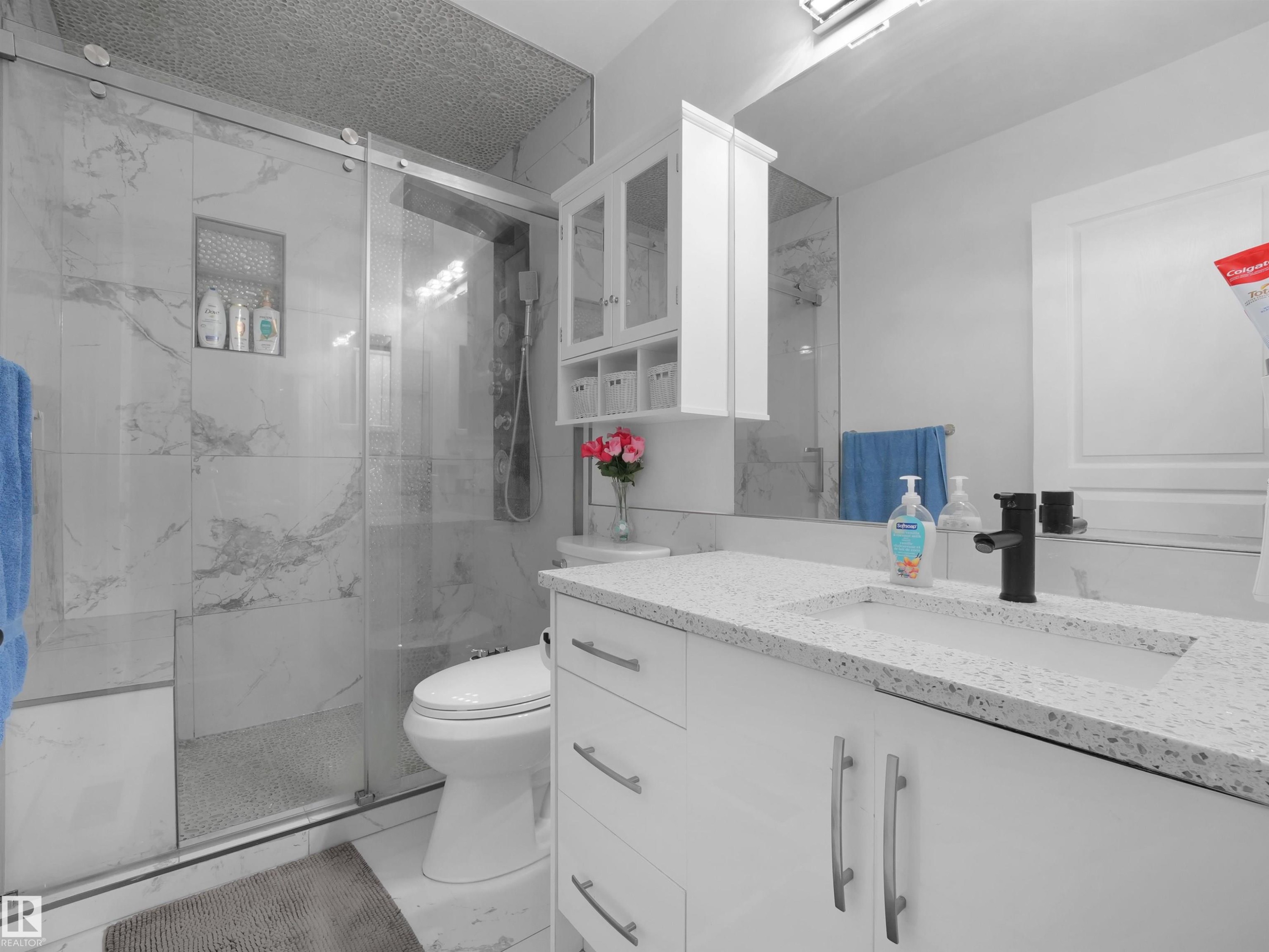 Walk-in shower with clear glass enclosure, built-in niche, and marble-look tile surround - 2418 32B Street, Edmonton, AB