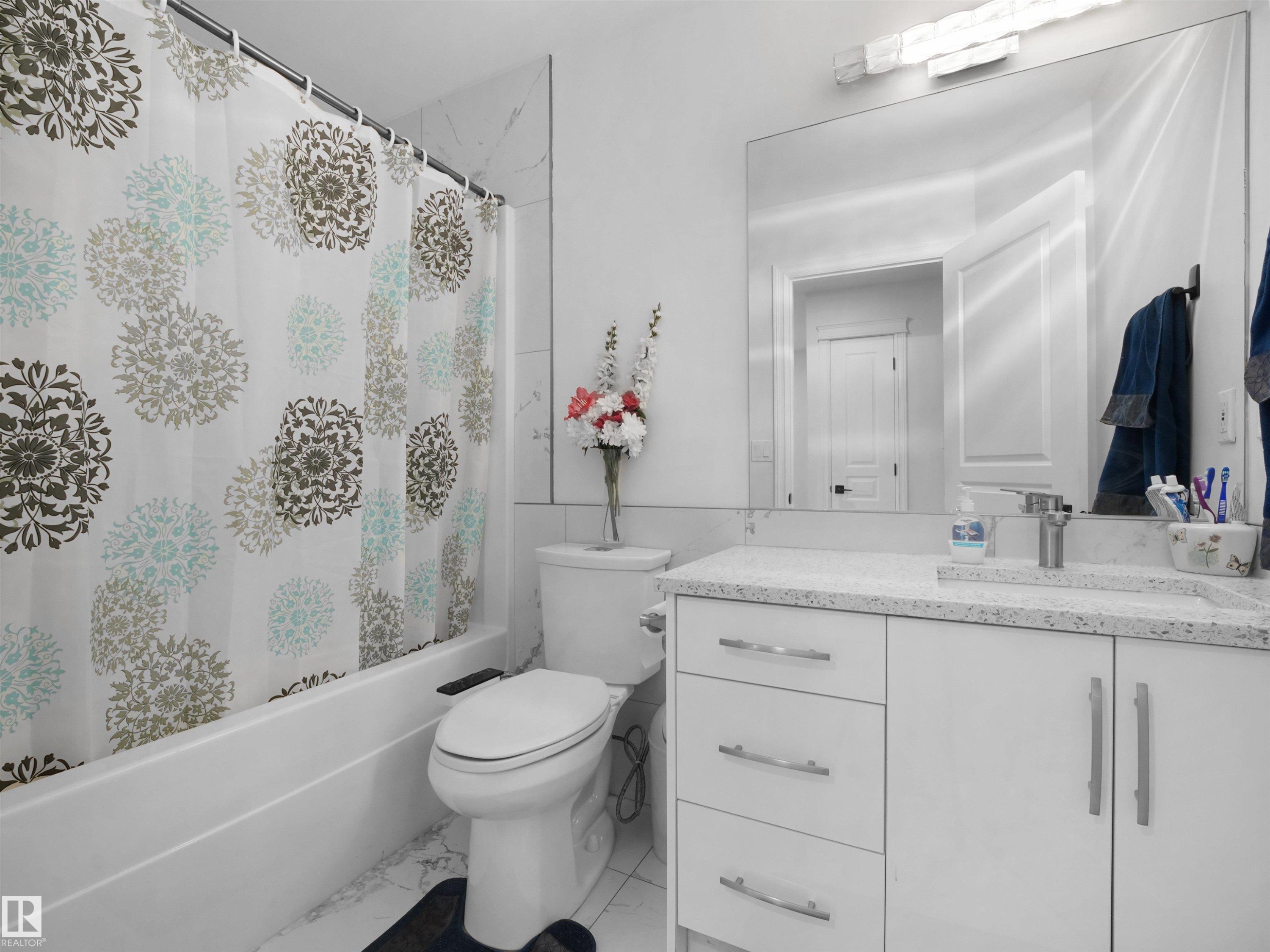 Bathroom featuring a white vanity with a light speckled countertop, under-mount sink, and chrome fixtures - 2418 32B Street, Edmonton, AB