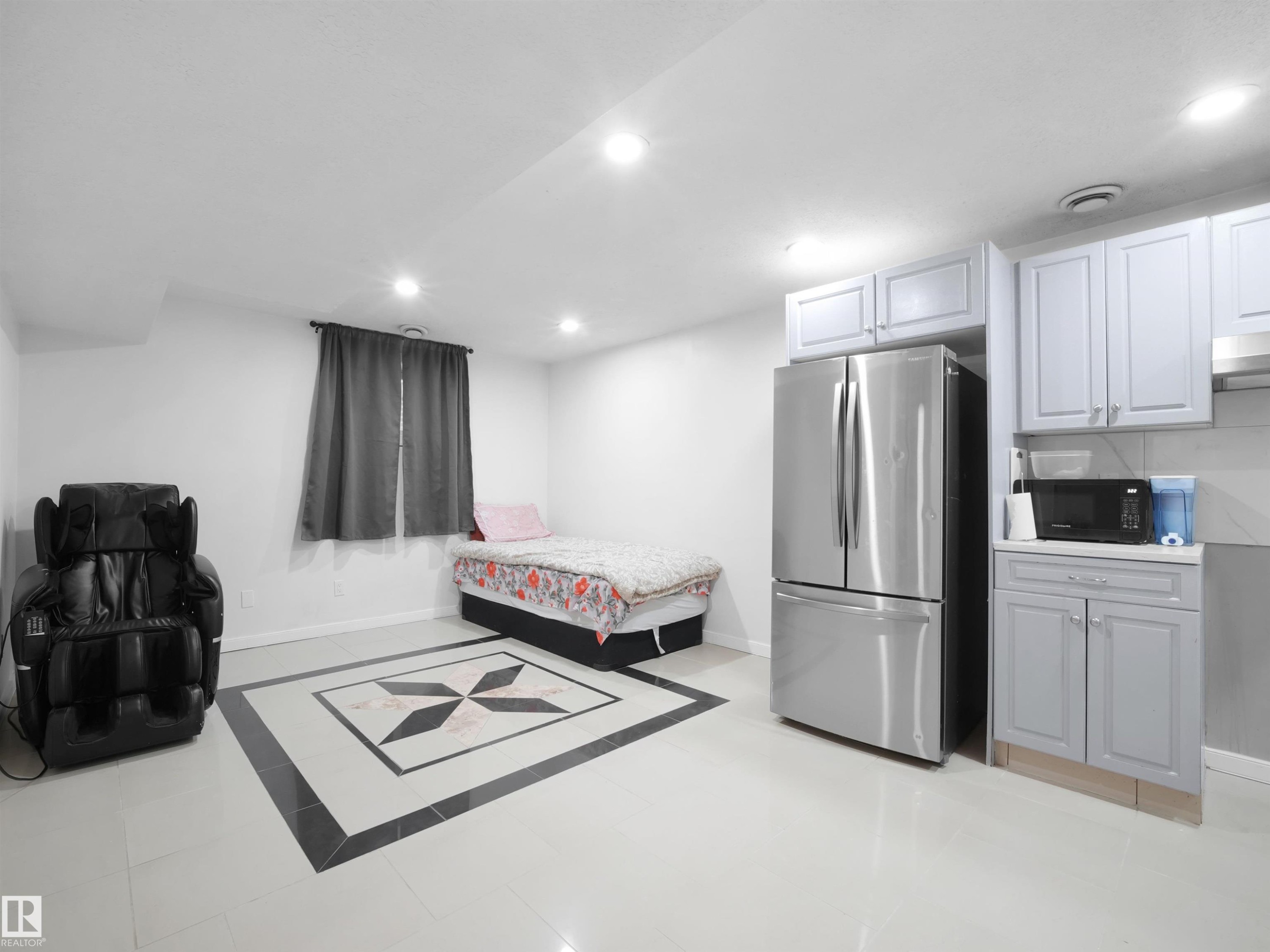 Open concept space featuring light-toned flooring with a central dark-and-light tile inlay - 2418 32B Street, Edmonton, AB