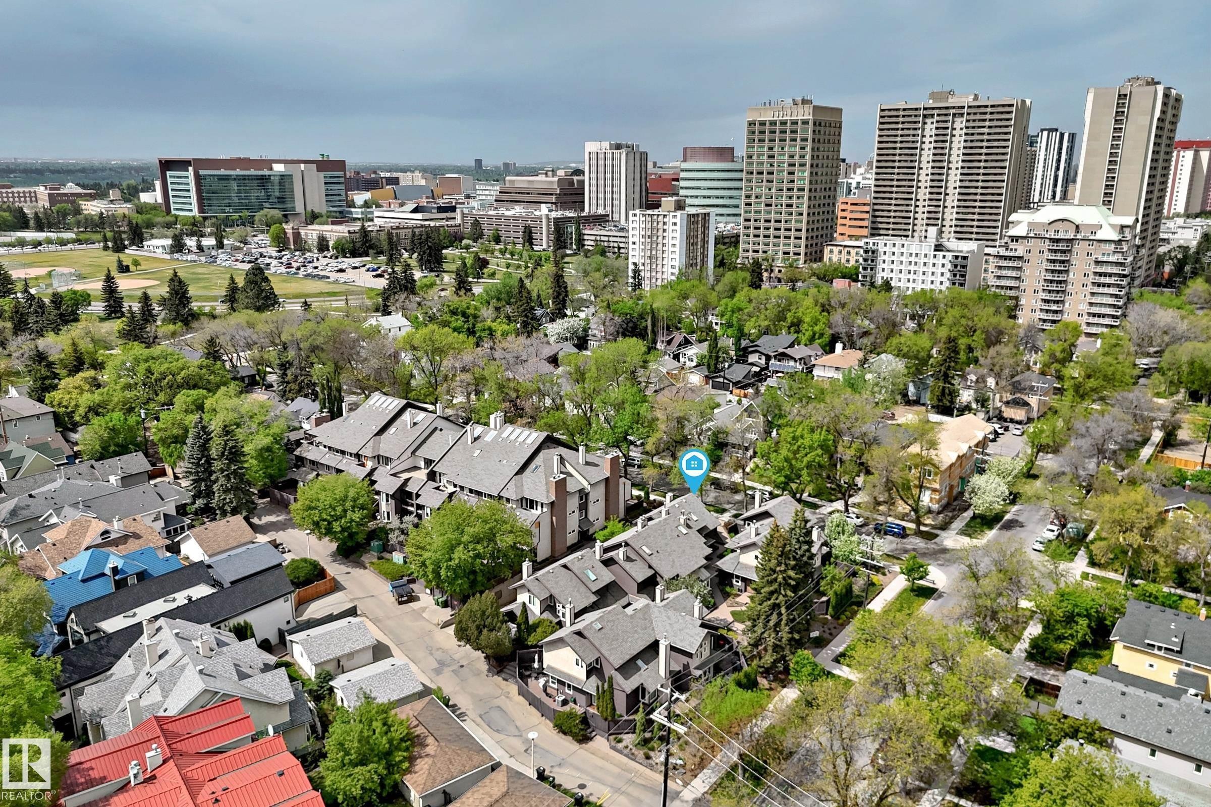 Aerial perspective showcasing residential properties with a backdrop of urban structures and green spaces - 7930 111 Street, Edmonton, AB - Outdoor With View