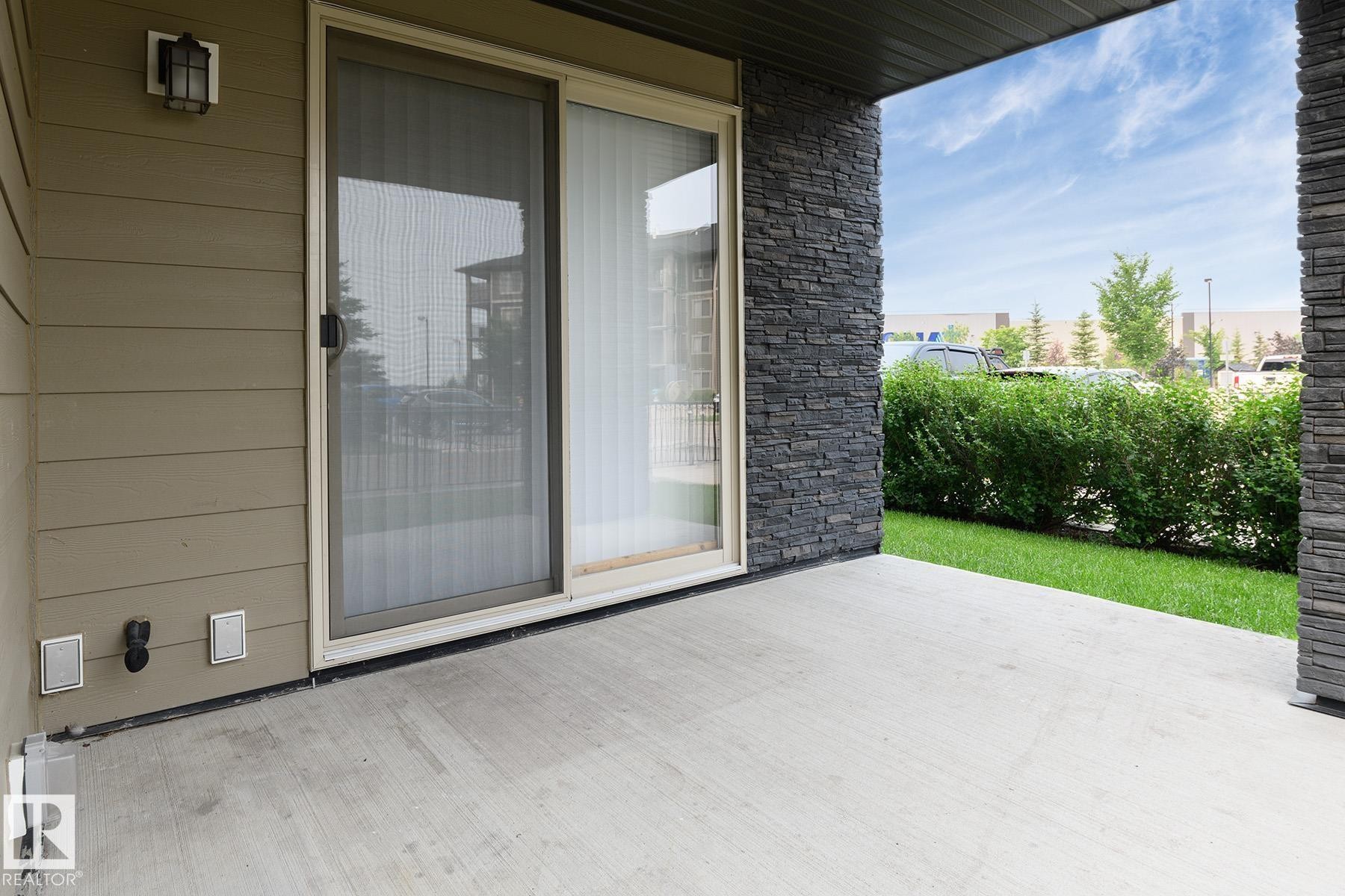 Concrete patio with stone accent wall and sliding glass door - 102 25 Element Dr, St. Albert, AB
