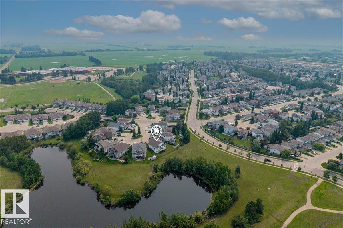 Aerial perspective showcasing a residential area bordered by open fields and natural water features - 215 Westerra Point(E), Stony Plain, AB