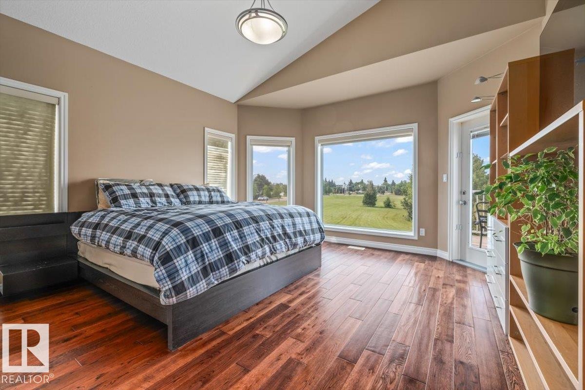 Spacious room featuring vaulted ceilings, wood-finish flooring, a large picture window, a glass-paned door, and built-in shelving with drawers - 215 Westerra Point(E), Stony Plain, AB