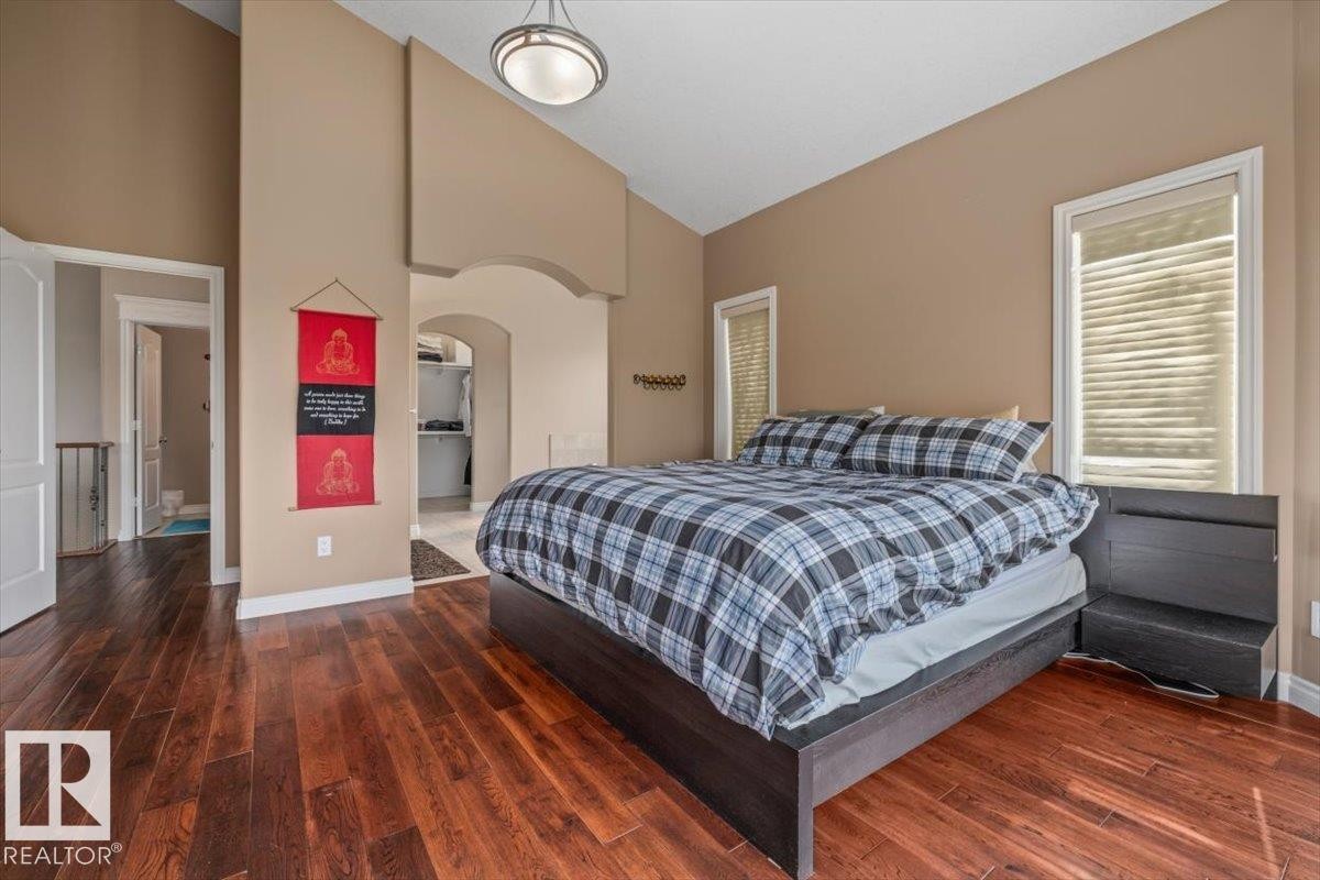 Vaulted ceiling bedroom featuring rich wood-finish flooring, warm neutral wall tones, and arched entryway - 215 Westerra Point(E), Stony Plain, AB