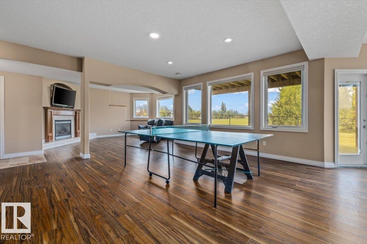 Spacious lower-level area featuring wood-finish flooring, recessed lighting, and large windows providing ample natural light - 215 Westerra Point(E), Stony Plain, AB