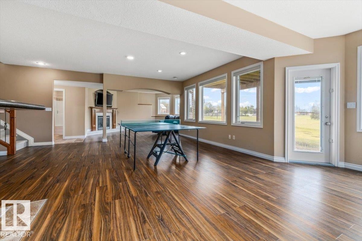 Spacious lower level featuring wood-finish flooring, recessed lighting, and a fireplace with a wood mantle - 215 Westerra Point(E), Stony Plain, AB