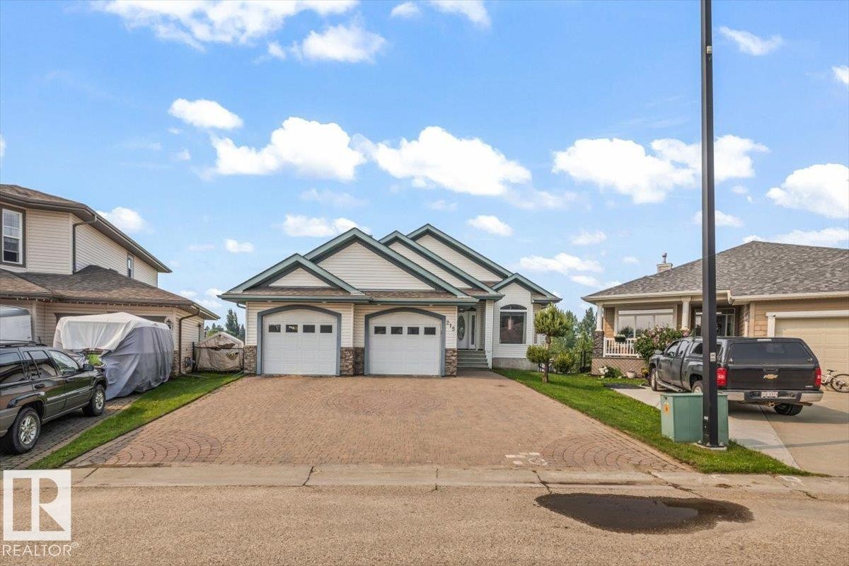 Ranch-style residence featuring a two-car garage with arched doors, stone veneer accents, and a gabled roofline - 215 Westerra Point(E), Stony Plain, AB